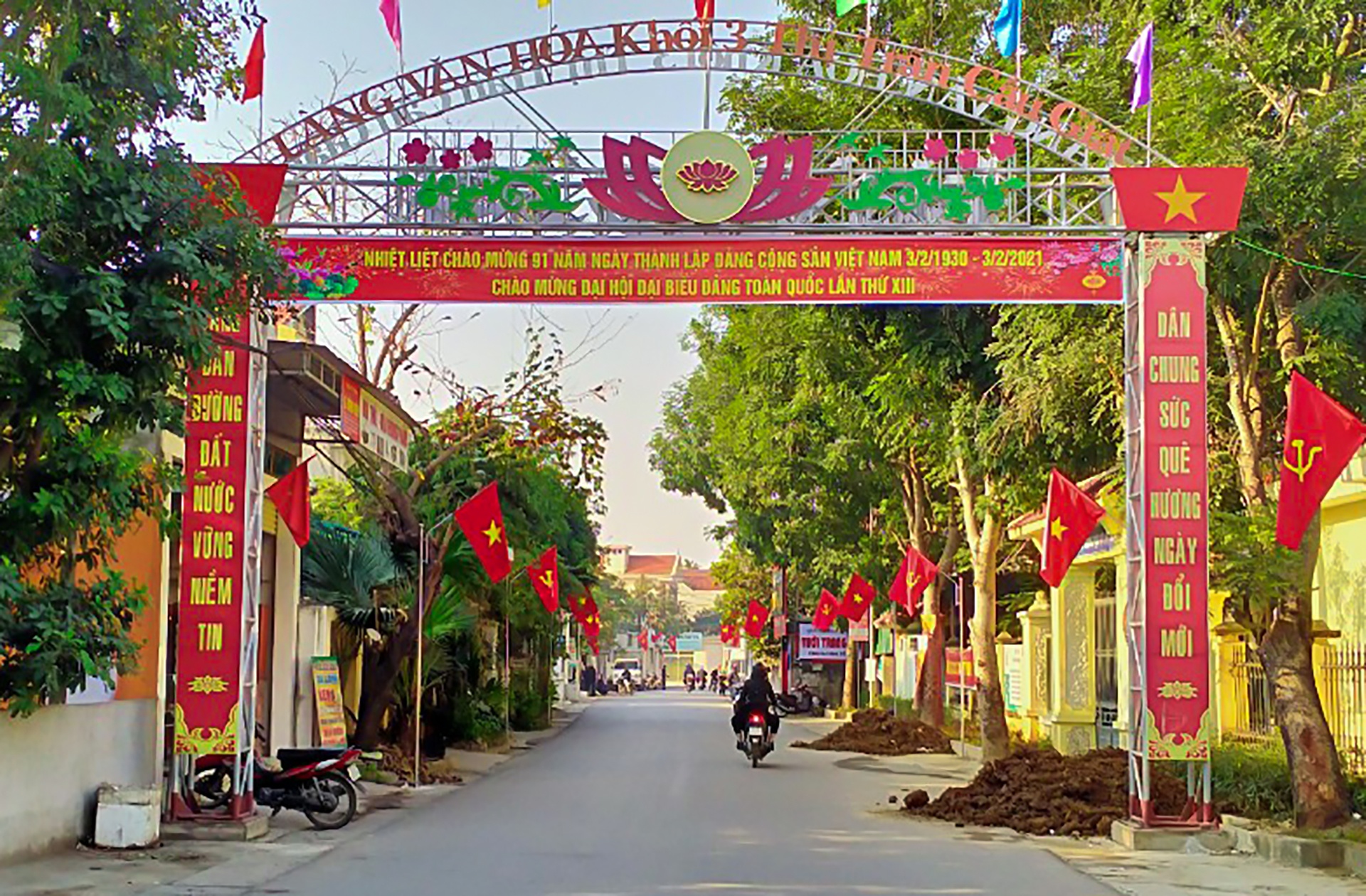 Cờ Đảng, cờ Tổ quốc đỏ rực tại một con ng&otilde; ở khối 3, thị trấn Cầu Gi&aacute;t, huyện Quỳnh Lưu