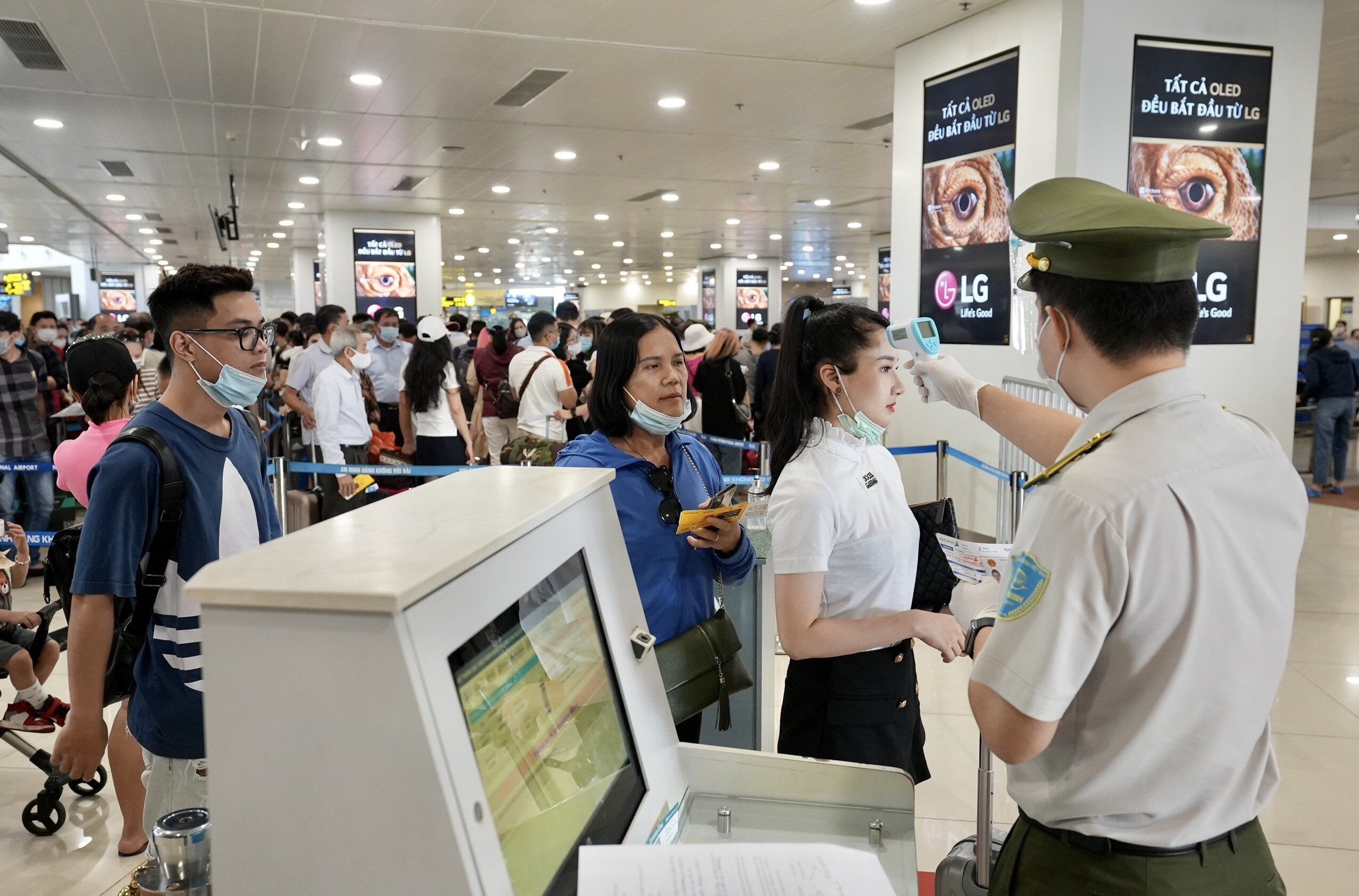 Nh&acirc;n vi&ecirc;n an ninh h&agrave;ng kh&ocirc;ng s&acirc;n bay Nội B&agrave;i đo th&acirc;n nhiệt cho h&agrave;nh kh&aacute;ch