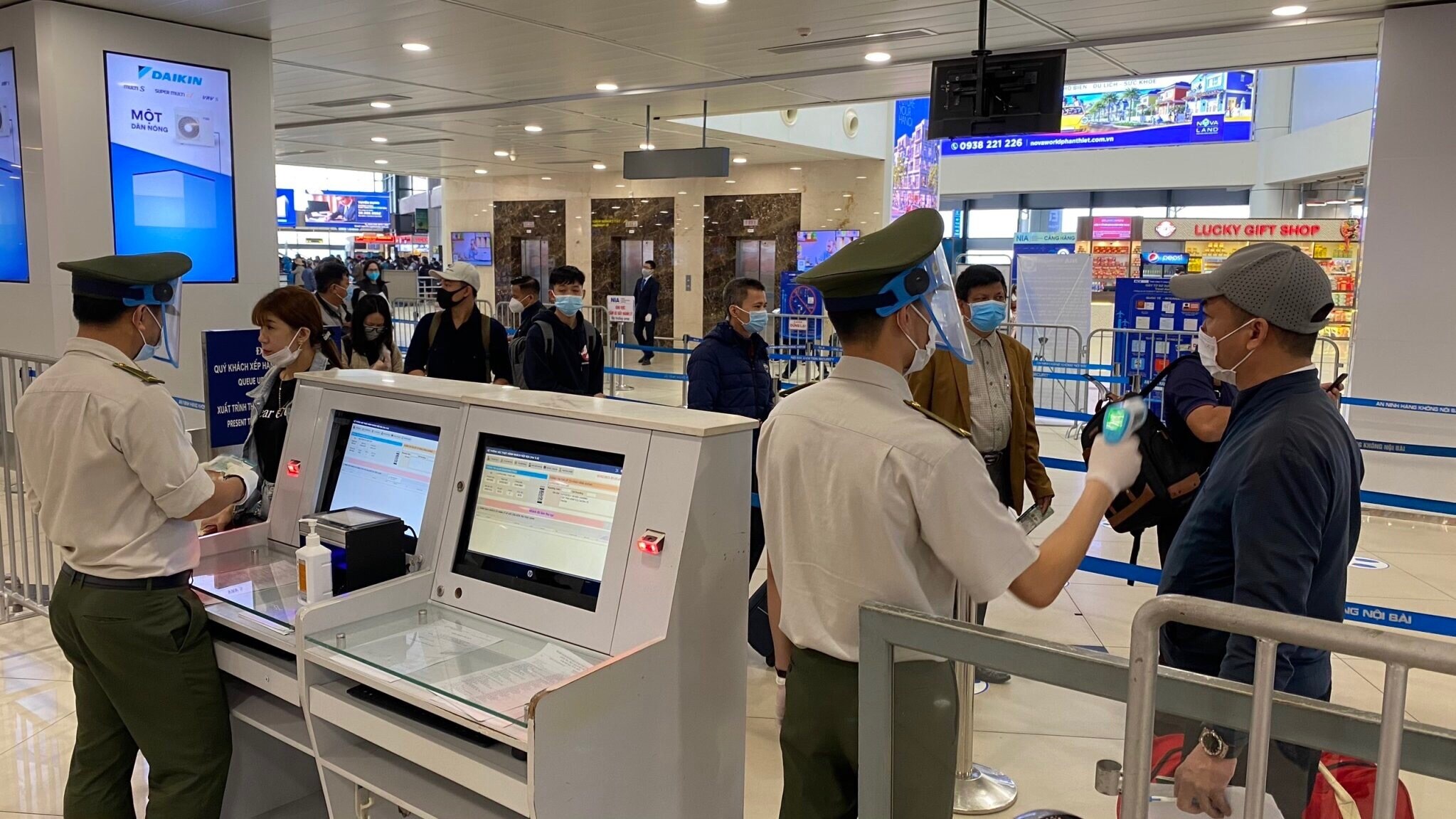 Nh&acirc;n vi&ecirc;n ANHK đo th&acirc;n nhiệt cho h&agrave;nh kh&aacute;ch. Lực lượng An ninh h&agrave;ng kh&ocirc;ng Nội B&agrave;i được trang bị đầy đủ găng tay, khẩu trang, tấm chắn giọt bắn trong khi l&agrave;m việc.