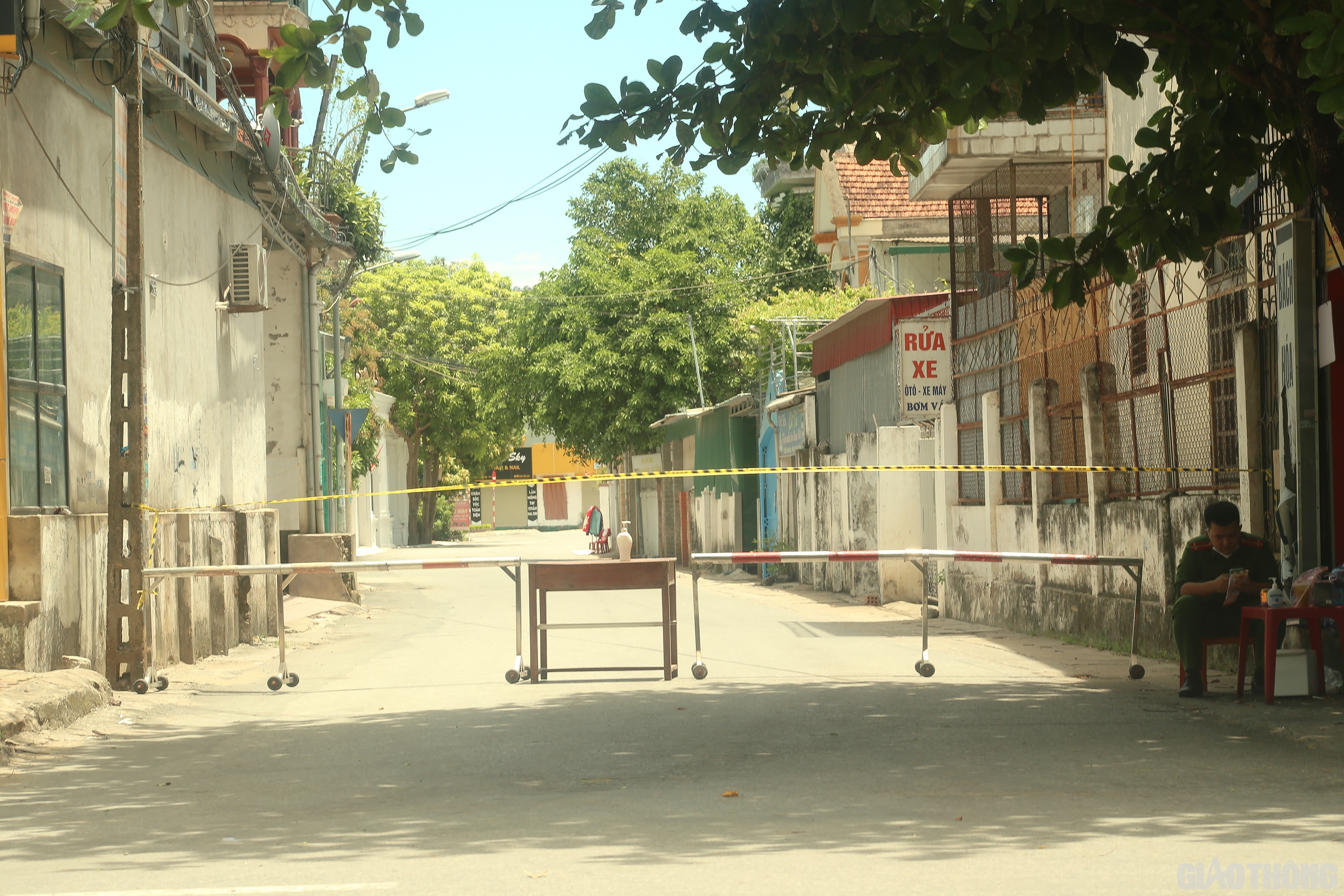 Ở một con ng&otilde; kh&aacute;c tr&ecirc;n đường H&agrave; Huy Tập, b&ecirc;n trong khu phong tỏa kh&ocirc;ng một b&oacute;ng người, nh&agrave; n&agrave;o cũng ở k&iacute;n trong nh&agrave;. Tranh thủ l&uacute;c kh&ocirc;ng c&oacute; người chuyển đồ v&agrave;o trong, một chiến sĩ C&ocirc;ng an trực chốt ăn tạm b&aacute;nh m&igrave; l&oacute;t bụng qua trưa. (Ảnh Sỹ H&ograve;a)