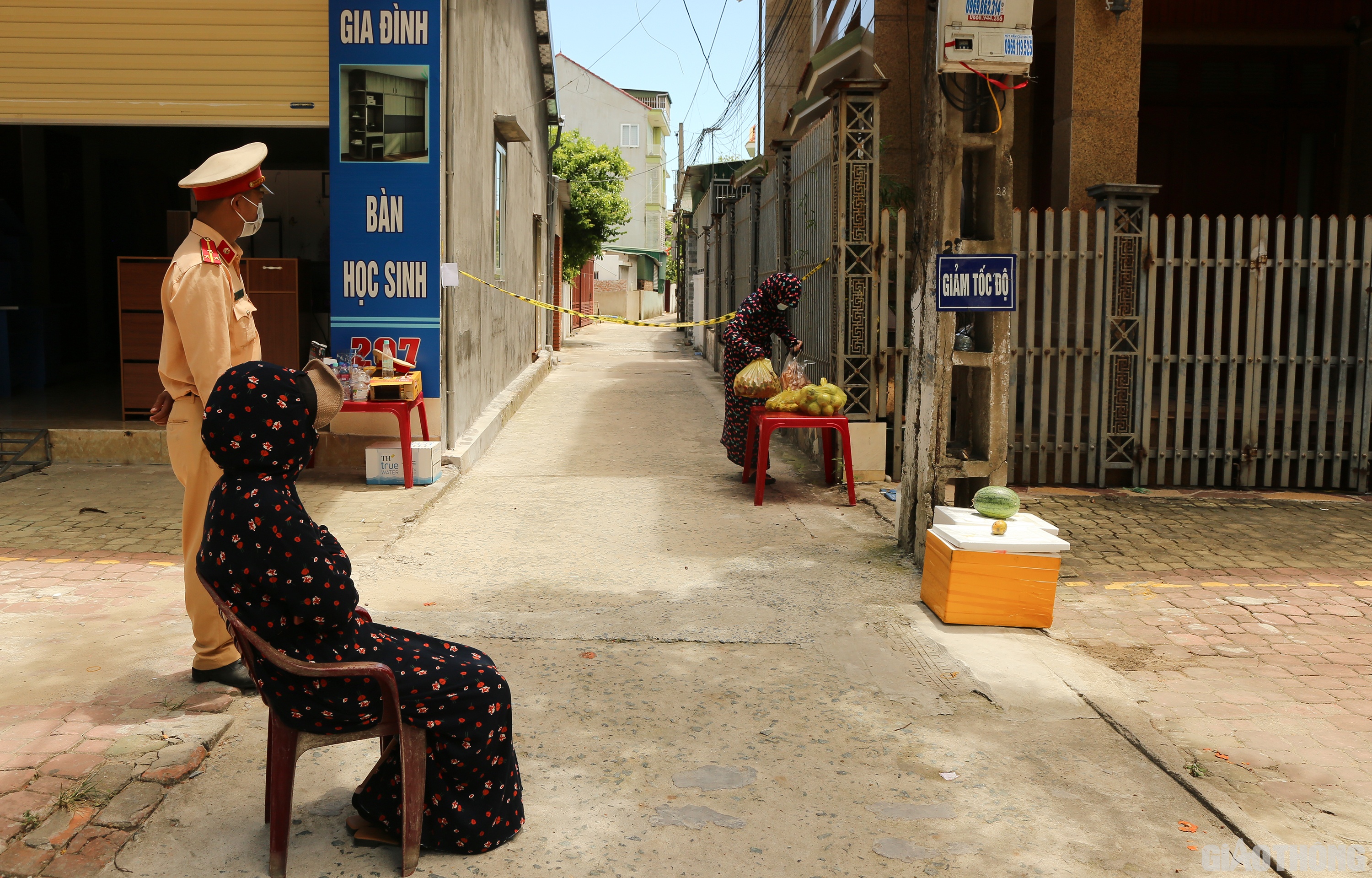 Một người phụ nữ trong khu phong tỏa ở phường H&agrave; Huy Tập, TP Vinh tr&ugrave;m k&iacute;n người để tr&aacute;nh nắng đi bộ ra chốt phong tỏa ở ng&otilde; 207 đường H&agrave; Huy Tập nhận đồ ăn đặt mua được ship đến. (Ảnh Sỹ H&ograve;a)