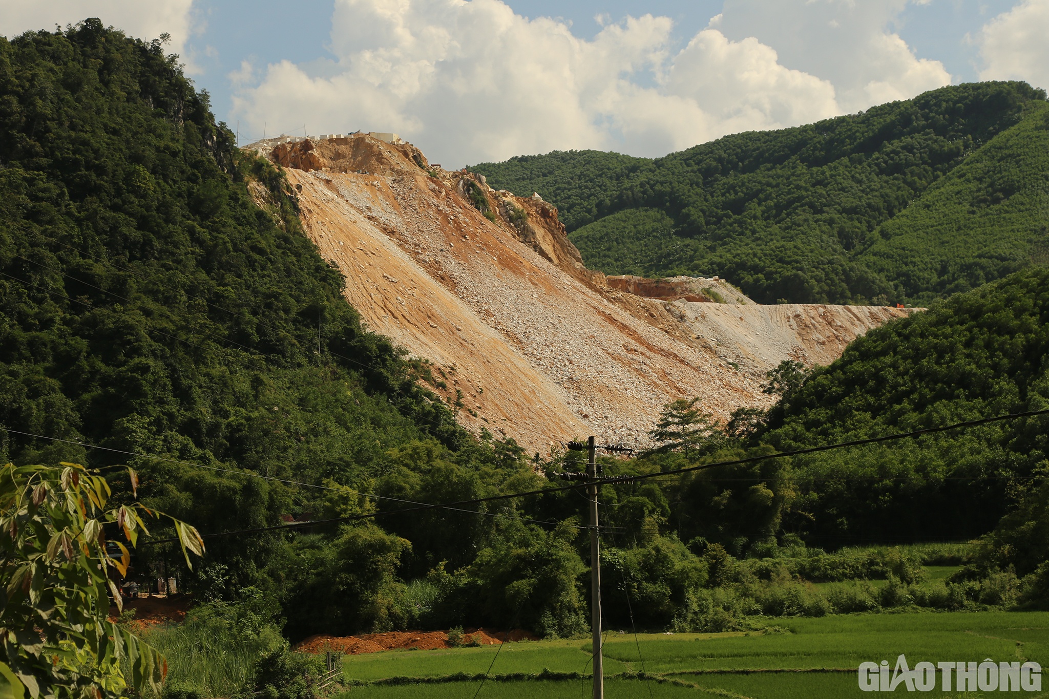 Từ xa đ&atilde; nh&igrave;n thấy một vạt rừng rộng lớn bị bạt trắng; đất đ&aacute; thải được đổ tr&agrave;n từ tr&ecirc;n n&uacute;i cao xuống dưới đất.