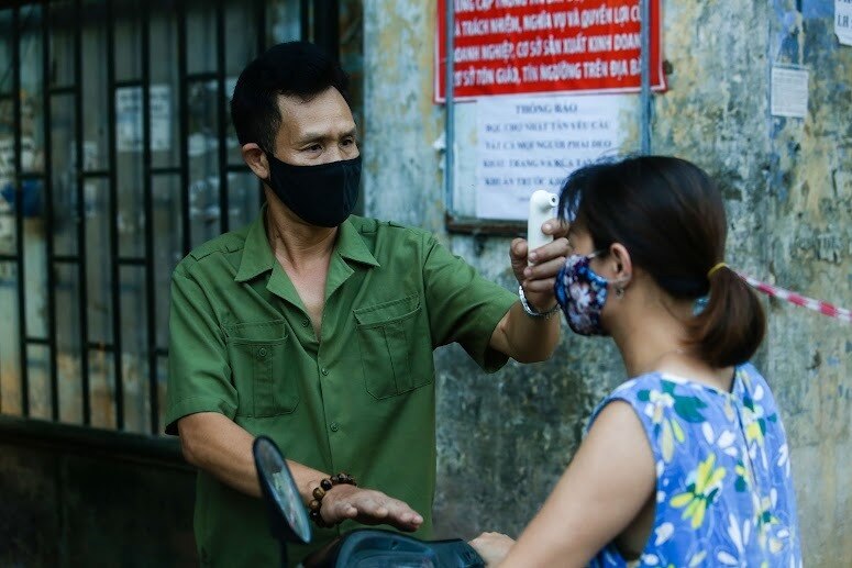 Khi đến chợ, mọi người d&acirc;n sẽ được đo nhiệt độ v&agrave; nhắc nhở đeo khẩu trang, giữ khoảng c&aacute;ch an to&agrave;n.