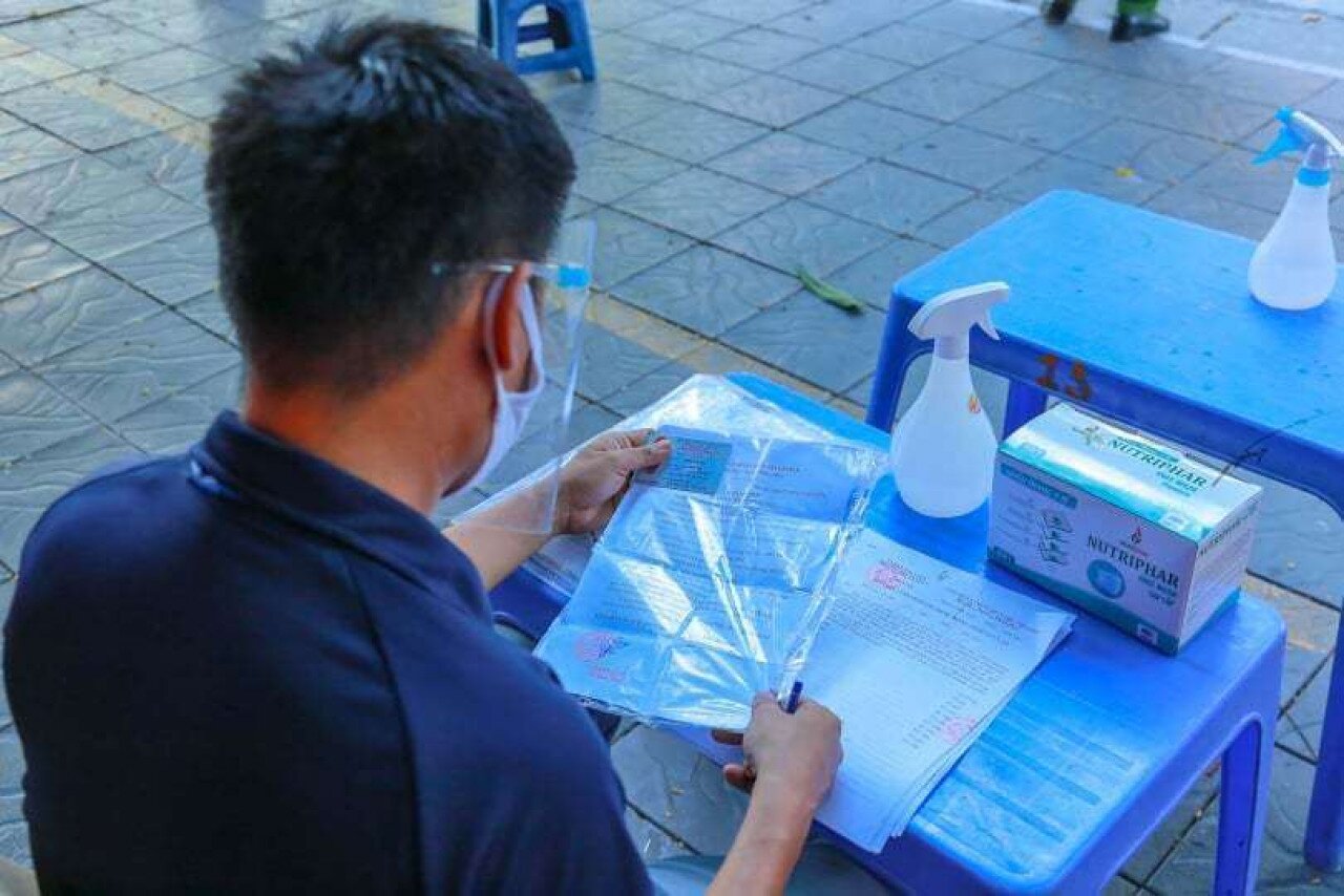 Một cán bộ UBND phường Thanh Nhàn đang kiểm tra, xác minh một trường hợp ra đường khi không cần thiết.