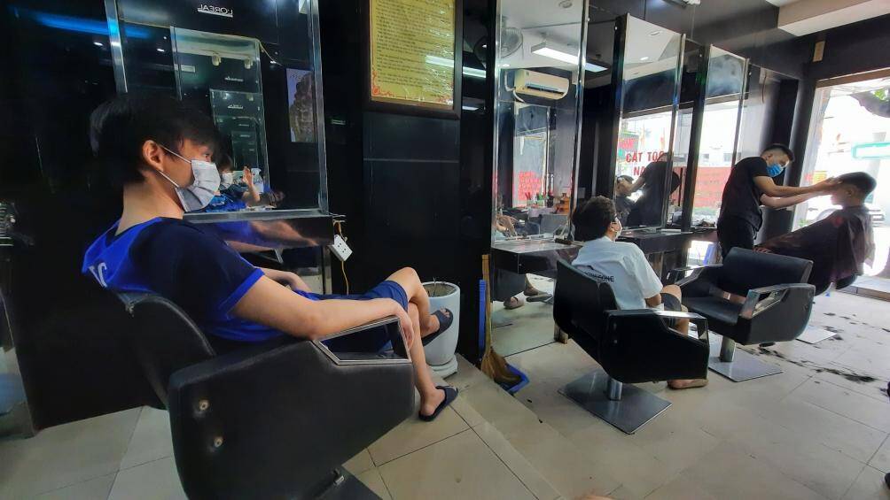 Những người đến cắt t&oacute;c tại đ&acirc;y được hướng dẫn khi ngồi chờ giữ khoảng c&aacute;ch, đeo khẩu trang đảm bảo ph&ograve;ng chống dịch Covid-19.