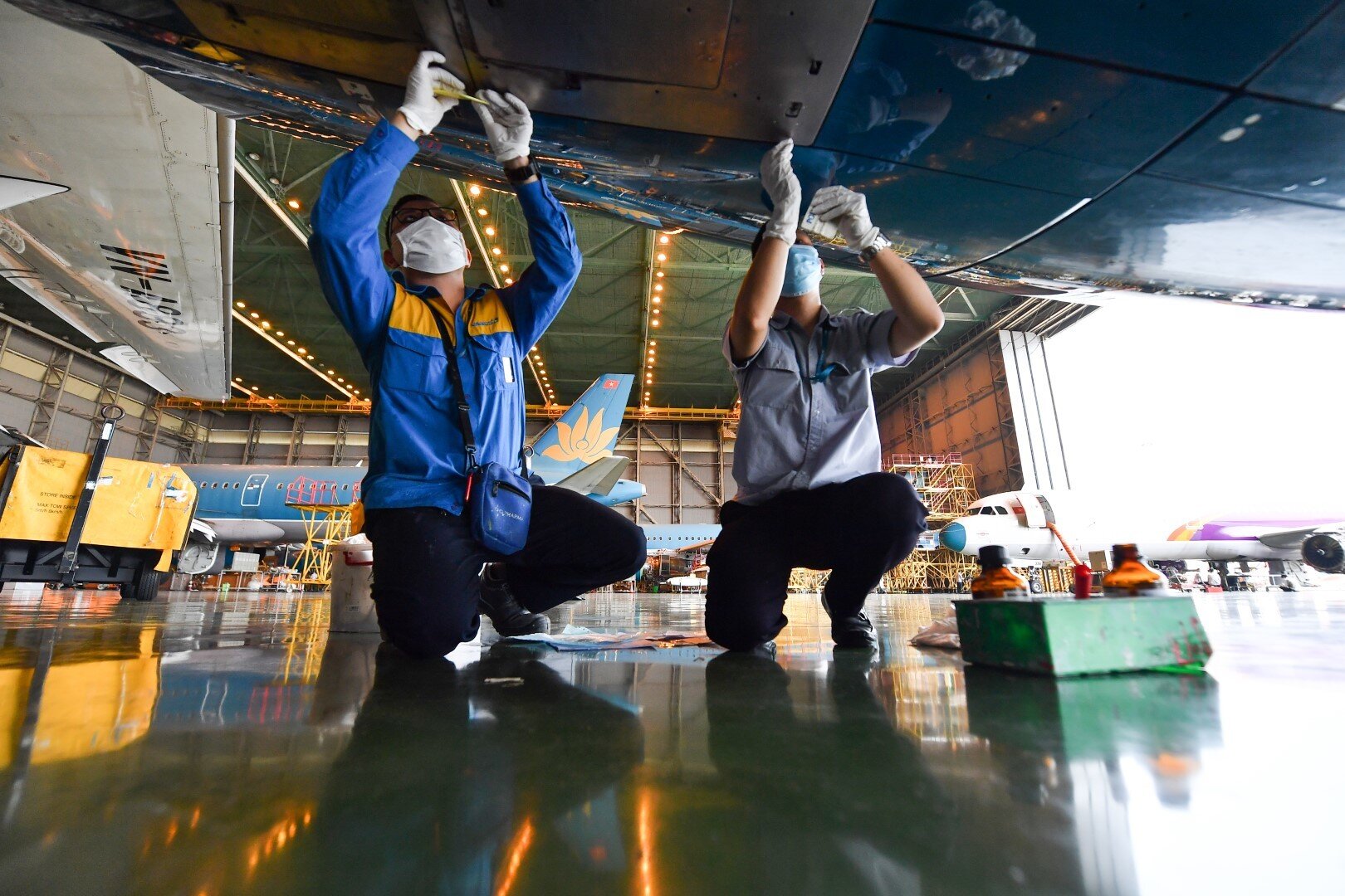 Một số nh&acirc;n vi&ecirc;n kh&aacute;c đang kiểm tra ốc v&iacute;t v&agrave; sơn của động cơ t&agrave;u bay Airbus A350.