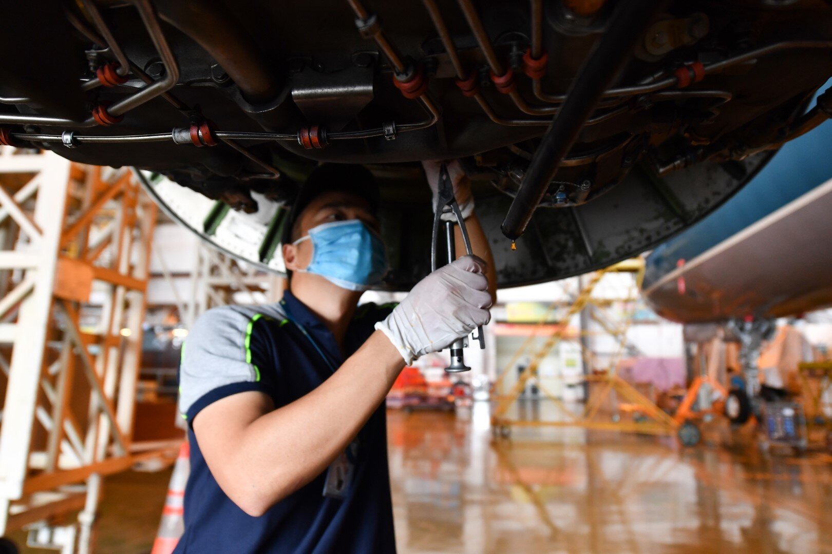 Một kỹ sư đang kiểm tra d&acirc;y bảo hiểm của động cơ m&aacute;y bay Airbus A321. Kh&ocirc;ng phải l&agrave; loại t&agrave;u bay lớn nhất của Vietnam Airlines, nhưng Airbus A321 l&agrave; đội t&agrave;u bay đ&ocirc;ng đảo nhất của h&atilde;ng với gần 70 chiếc, được khai th&aacute;c chủ lực tr&ecirc;n những đường bay tầm ngắn, tầm trung.