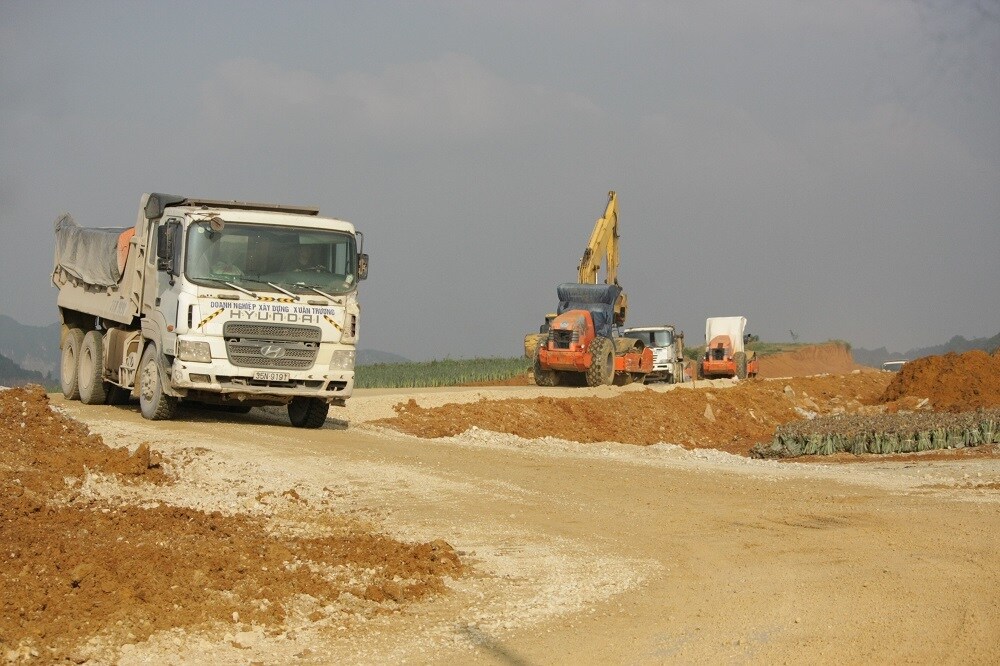 C&aacute;c xe vận chuyển vật liệu li&ecirc;n tục ra, v&agrave;o phục vụ thi c&ocirc;ng. "L&aacute;i xe điều khiển phương tiện vận chuyển vật liệu từ ngoại tỉnh đến c&ocirc;ng trường tại Ninh B&igrave;nh đều được y&ecirc;u cầu ngồi tr&ecirc;n xe trong suốt qu&aacute; tr&igrave;nh bốc dỡ, hạn chế việc tiếp x&uacute;c với lao động tại khu vực thi c&ocirc;ng", &ocirc;ng Đ&agrave;m Đức Ngọc, chỉ huy g&oacute;i thầu số 10 cho hay.