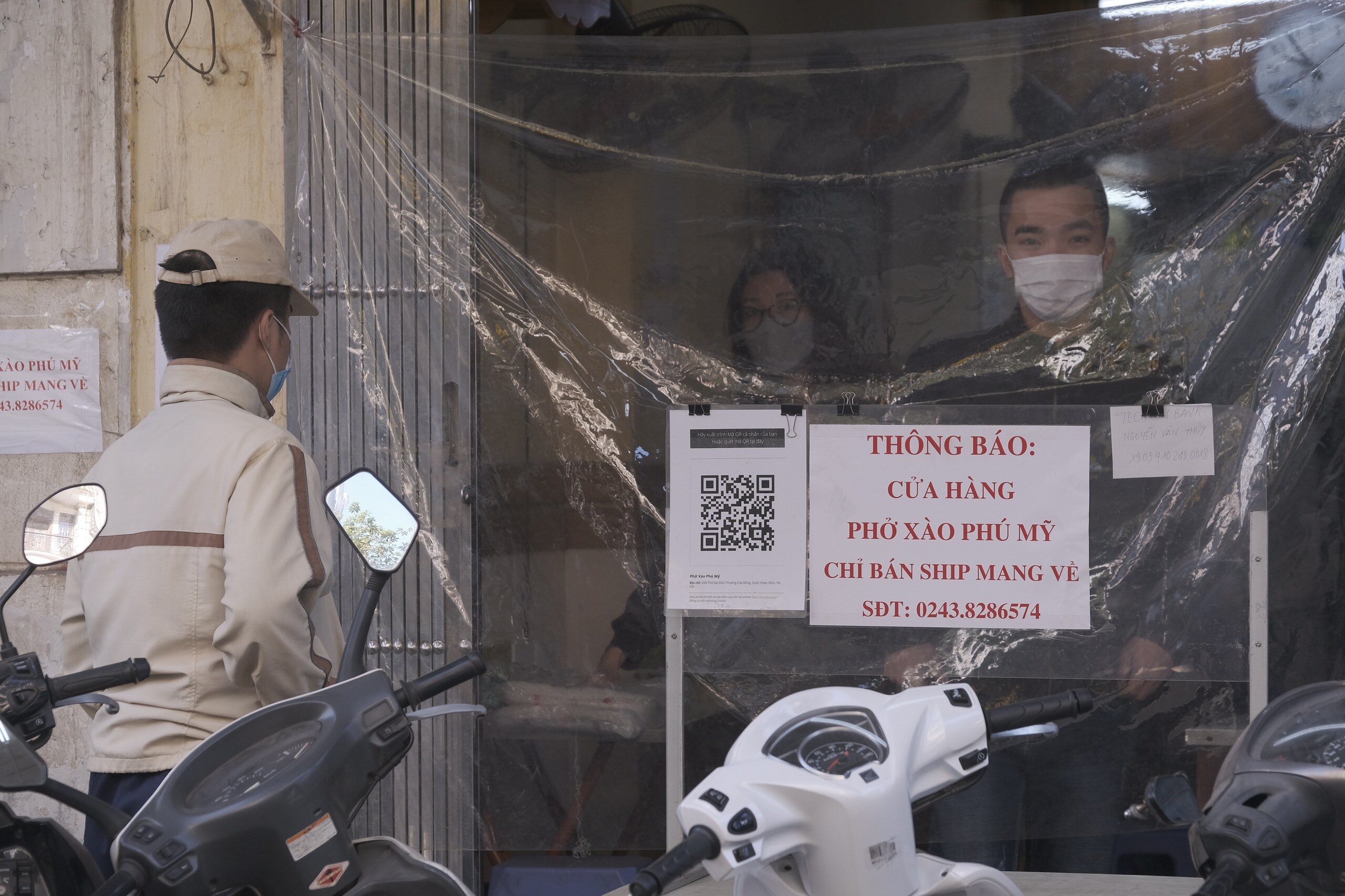Ghi nhận của PV cho thấy, ngay từ s&aacute;ng nay, nhiều cửa h&agrave;ng ở khu vực nguy cơ cao tại quận Ho&agrave;n Kiếm đ&atilde; dừng b&aacute;n tại chỗ. Cửa h&agrave;ng phở x&agrave;o ở phố B&aacute;t Đ&agrave;n, phường Cửa Đ&ocirc;ng, quận Ho&agrave;n Kiếm đ&atilde; căng tấm chắn để kh&aacute;ch kh&ocirc;ng v&agrave;o, y&ecirc;u cầu kh&aacute;ch đến mua h&agrave;ng mang về phải qu&eacute;t m&atilde; QR.