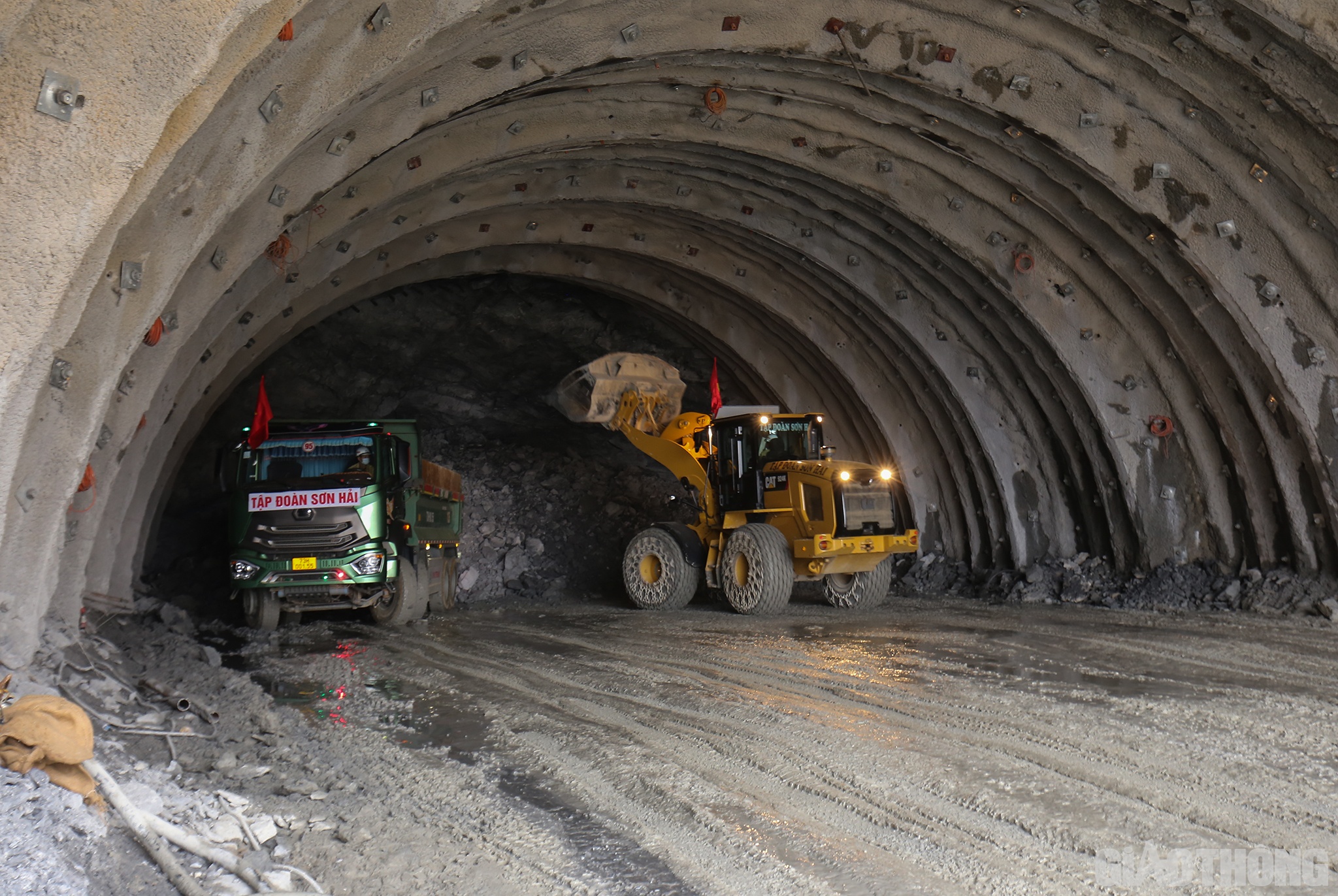 Tại c&ocirc;ng trường ph&iacute;a Nam hầm Trường Vinh, h&agrave;ng chục c&ocirc;ng nh&acirc;n v&agrave; xe m&aacute;y cả b&ecirc;n ngo&agrave;i lẫn trong hầm vẫn miệt m&agrave;i l&agrave;m việc. Tiếng c&ocirc;ng nh&acirc;n, tiếng động cơ xe tải, tiếng m&aacute;y cắt đ&aacute;&hellip; rộn vang cả một v&ugrave;ng.