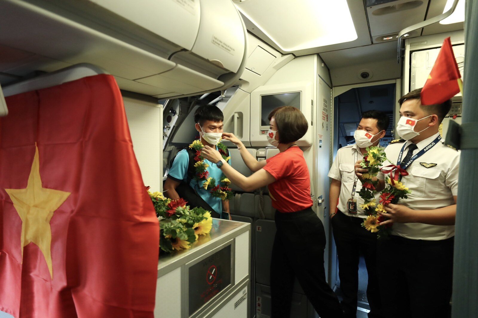 Tổ tiếp viên của chuyến bay trong trang phục áo cờ đỏ sao vàng chào mừng những người hùng quả cảm.