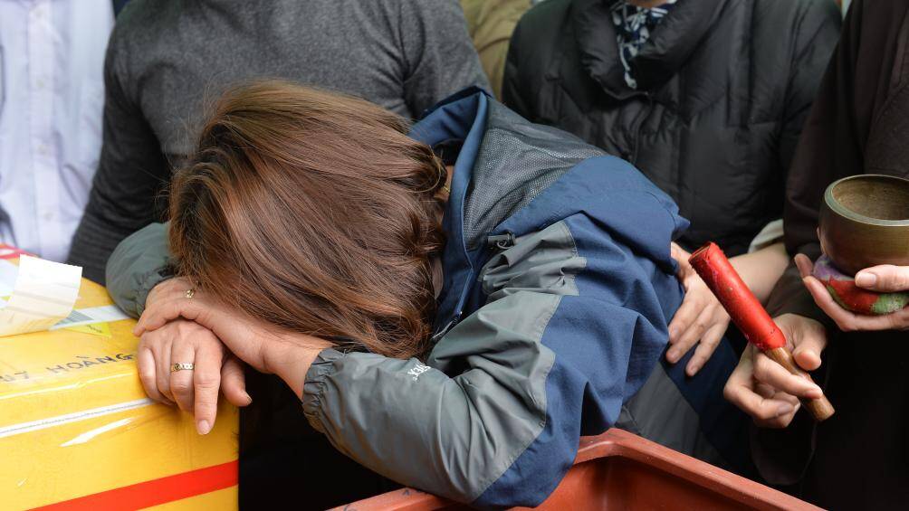 Chị Nguyễn Thị Minh - mẹ của 2 ch&aacute;u b&eacute; &ocirc;m tro cốt của hai con, khuỵu xuống kh&oacute;c như mưa.