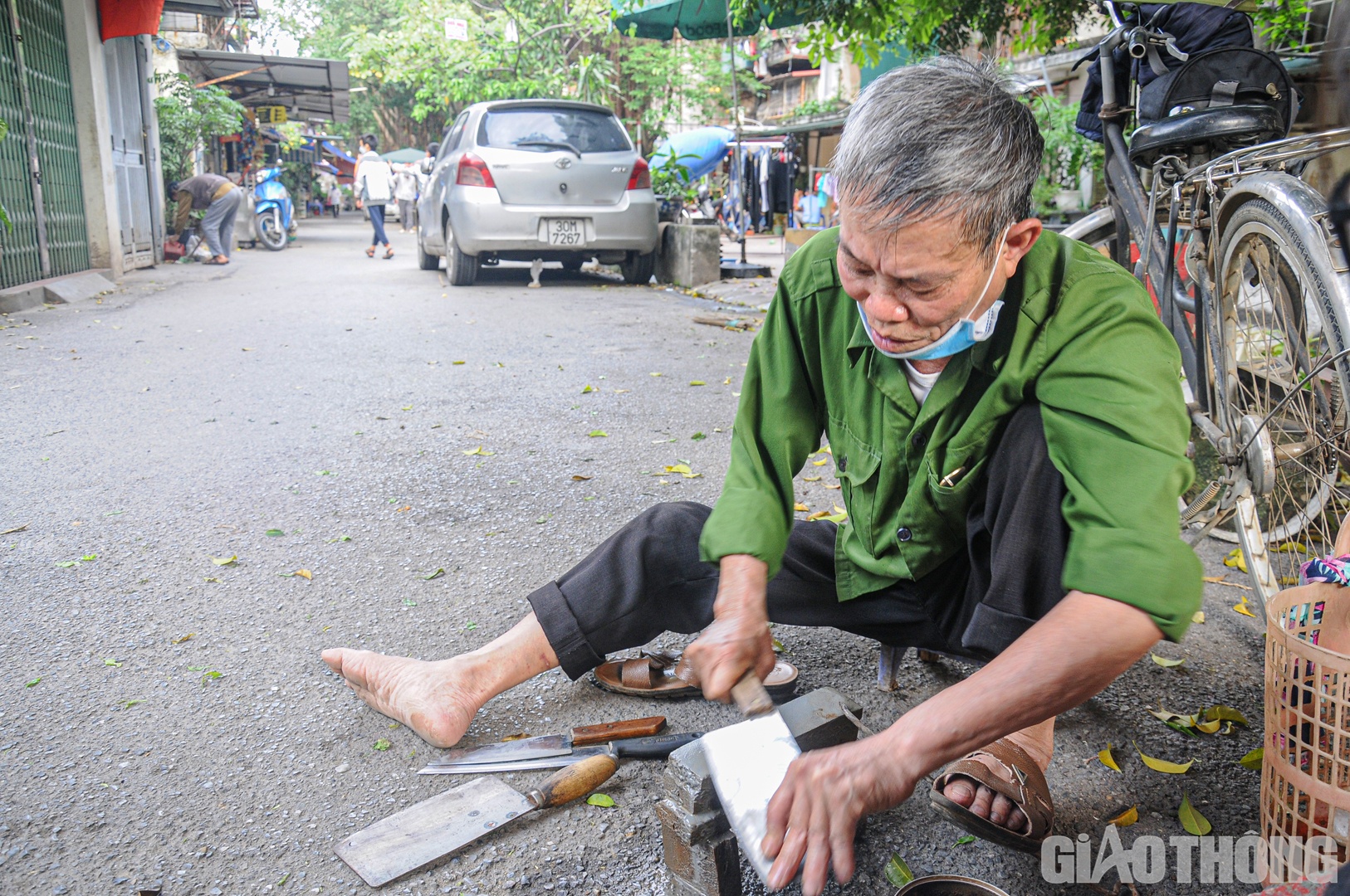 Người đ&agrave;n &ocirc;ng với m&aacute;i t&oacute;c muối ti&ecirc;u tập trung m&agrave;i dao trong khu tập thể Th&agrave;nh C&ocirc;ng.