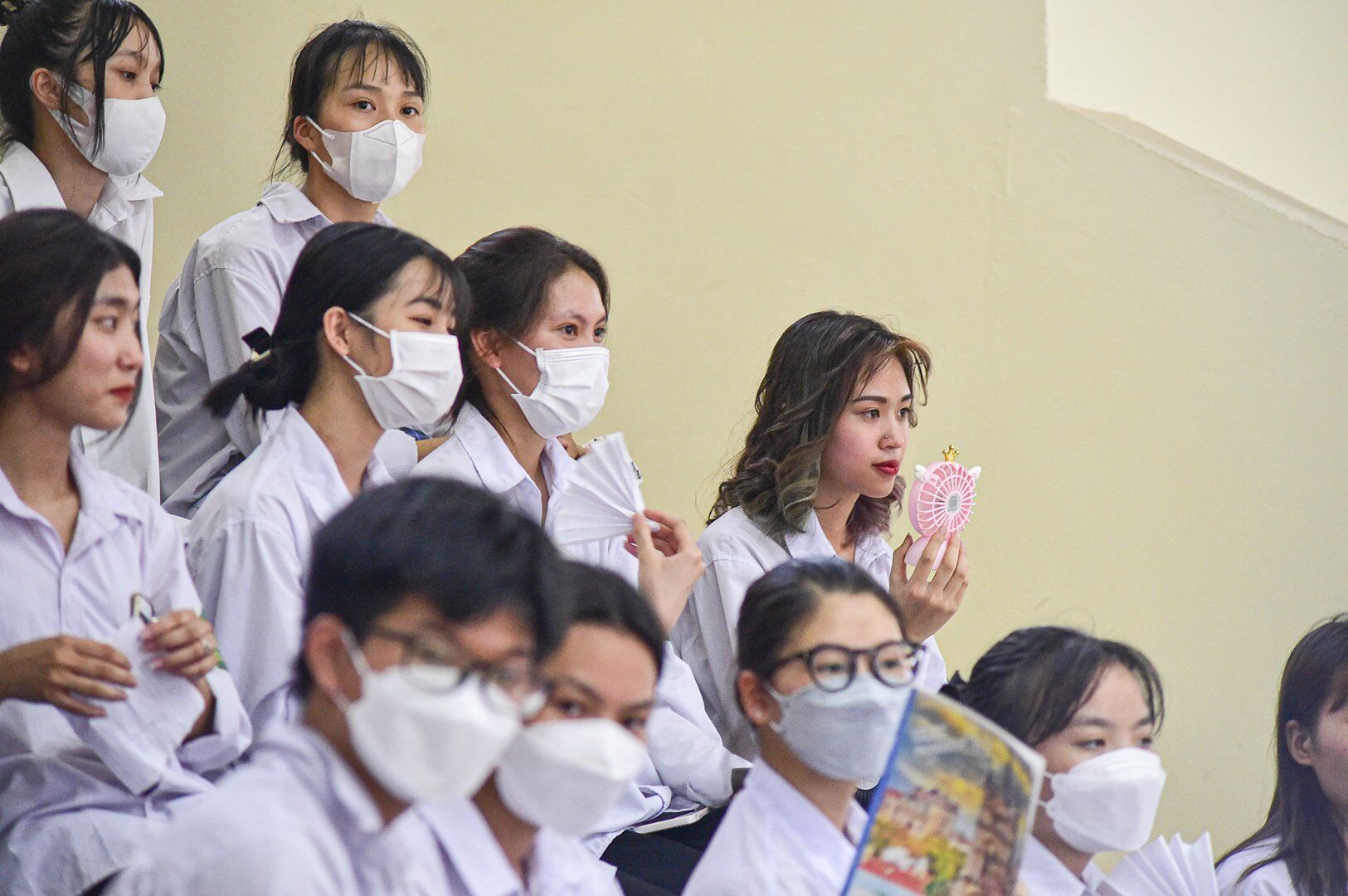 Do trời n&oacute;ng, điều h&ograve;a trong Nh&agrave; thi đấu kh&ocirc;ng đủ l&agrave;m m&aacute;t kh&ocirc;ng kh&iacute; n&ecirc;n nhiều em d&ugrave;ng quạt mini hoặc vở để quạt.