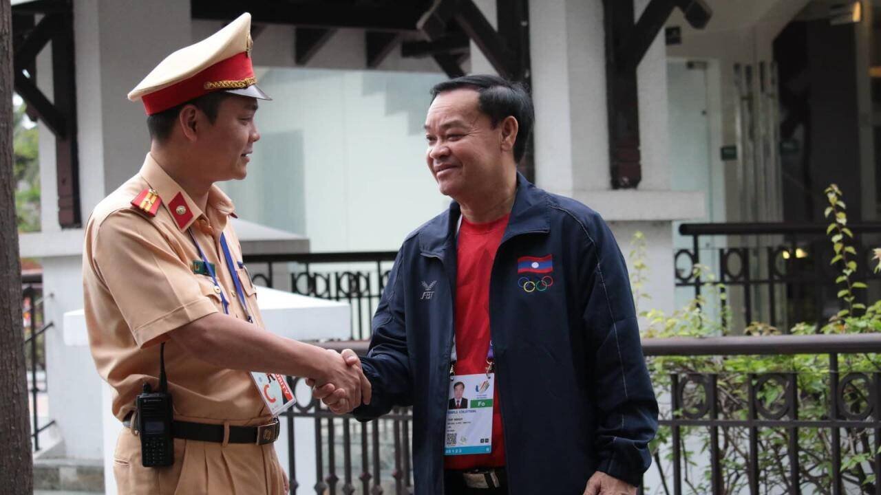C&aacute;n bộ CSGT Hà Nội ch&agrave;o hỏi, bắt tay với đại diện đoàn thể thao nước bạn Lào trước khi mời đo&agrave;n l&ecirc;n xe, xuất phát từ khách sạn đến nơi thi đấu.