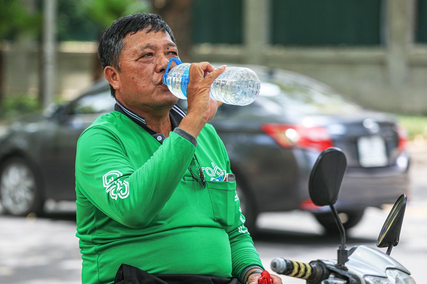 Để chống chọi với nắng n&oacute;ng, t&agrave;i xế xe &ocirc;m n&agrave;y phải li&ecirc;n tục uống nước.
