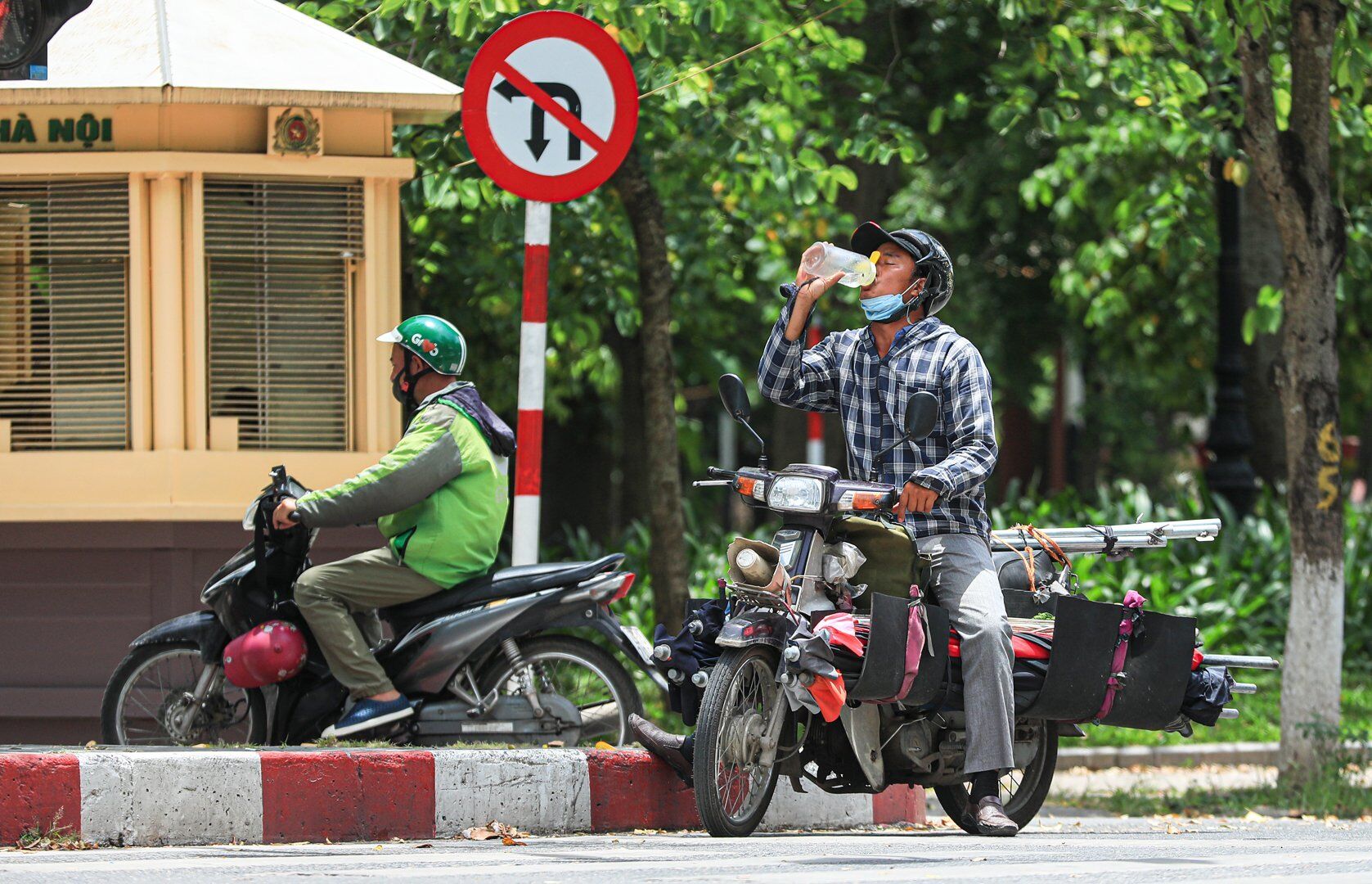 Một người tham gia giao th&ocirc;ng bằng xe m&aacute;y khi dừng đ&egrave;n đỏ cũng tranh thủ bổ sung nước v&agrave;o cơ thể.