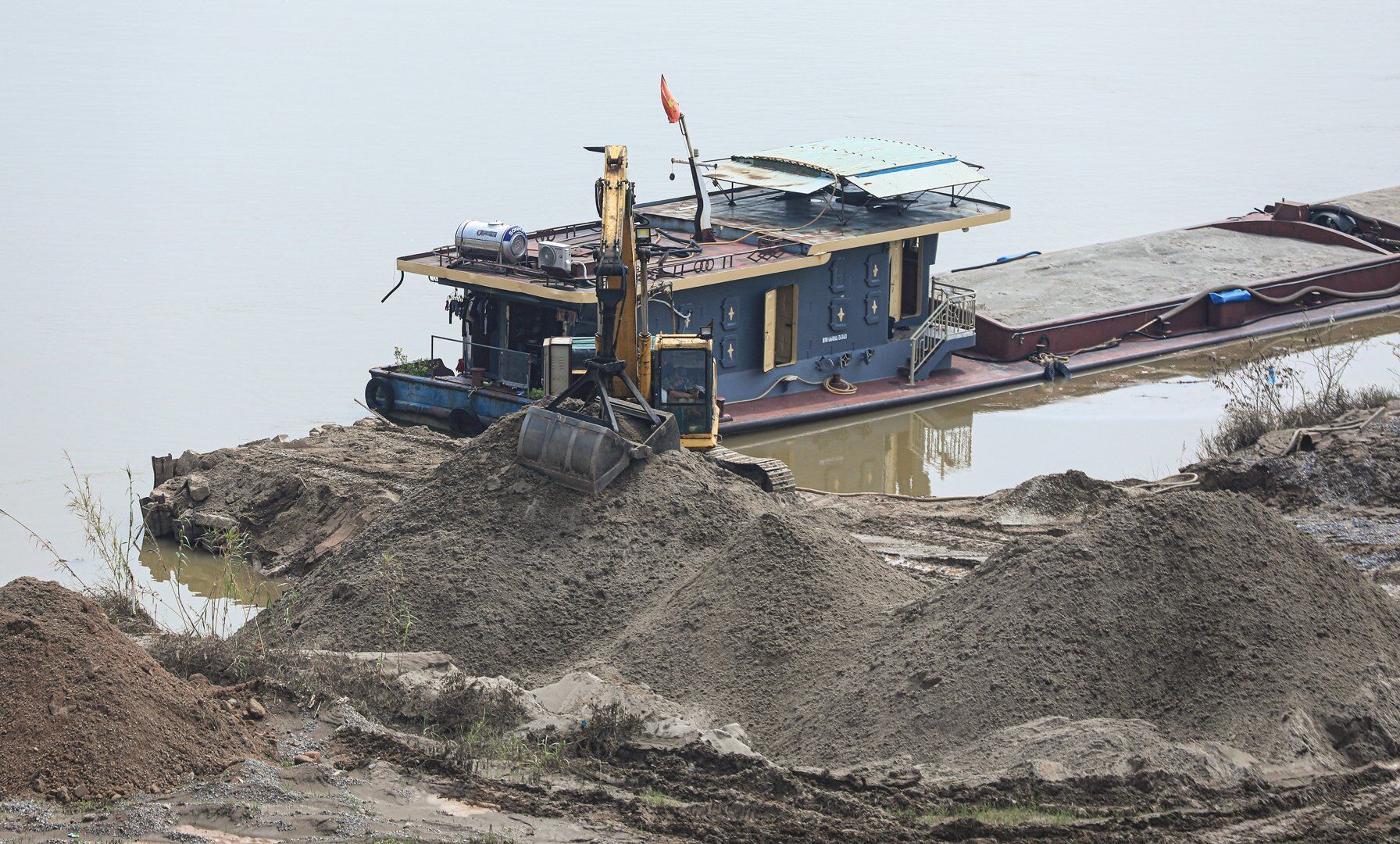 Tại khu đất b&atilde;i s&ocirc;ng Hồng, đoạn qua địa phận x&atilde; Vĩnh Ngọc, dễ d&agrave;ng ghi nhận cảnh tượng nhiều t&agrave;u chở c&aacute;t v&agrave; m&aacute;y x&uacute;c tấp nập hoạt động.