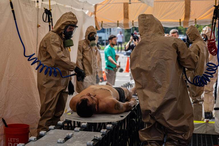 Một trong những nội dung diễn tập l&agrave; sơ cứu cho nạn nh&acirc;n phơi nhiễm với ph&oacute;ng xạ. Nh&acirc;n vi&ecirc;n cứu hộ tiến h&agrave;nh qu&eacute;t ph&oacute;ng xạ rồi đặt nạn nh&acirc;n l&ecirc;n c&aacute;ng, bọc phim tr&aacute;ng bạc l&ecirc;n người đ&agrave;n &ocirc;ng rồi đưa l&ecirc;n xe cứu thương.