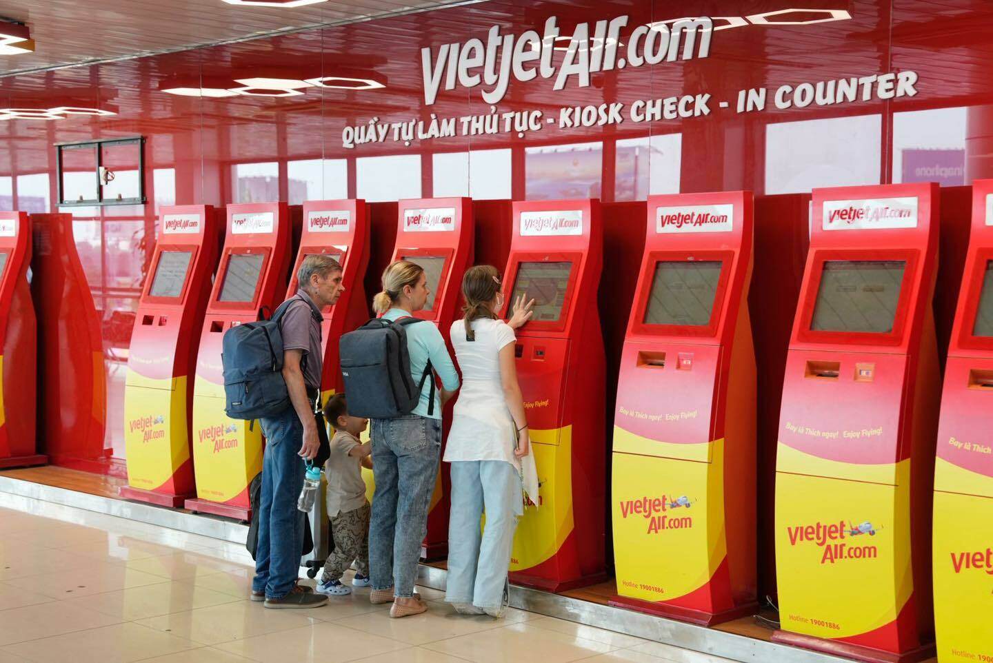 Một nh&oacute;m gia đ&igrave;nh người nước ngo&agrave;i tự l&agrave;m thủ tục check in tại c&aacute;c kiosk của h&atilde;ng Vietjet Air.