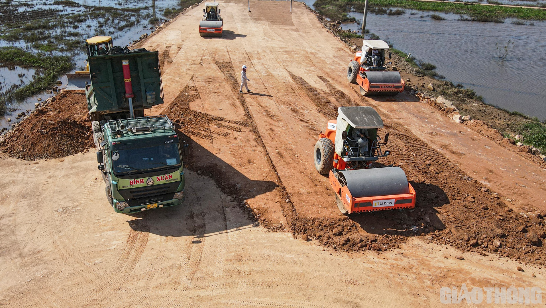 Trưa ngày 11/10, trên công trường dự án QL45 - Nghi Sơn, từng đoàn xe ủi, xe lu kéo nhau trở lại công địa sau chuỗi ngày mưa kéo dài. Tình trạng ngập lụt quanh khu vực thi công xuất hiện cản trở quá trình huy động thiết bị, vật liệu.