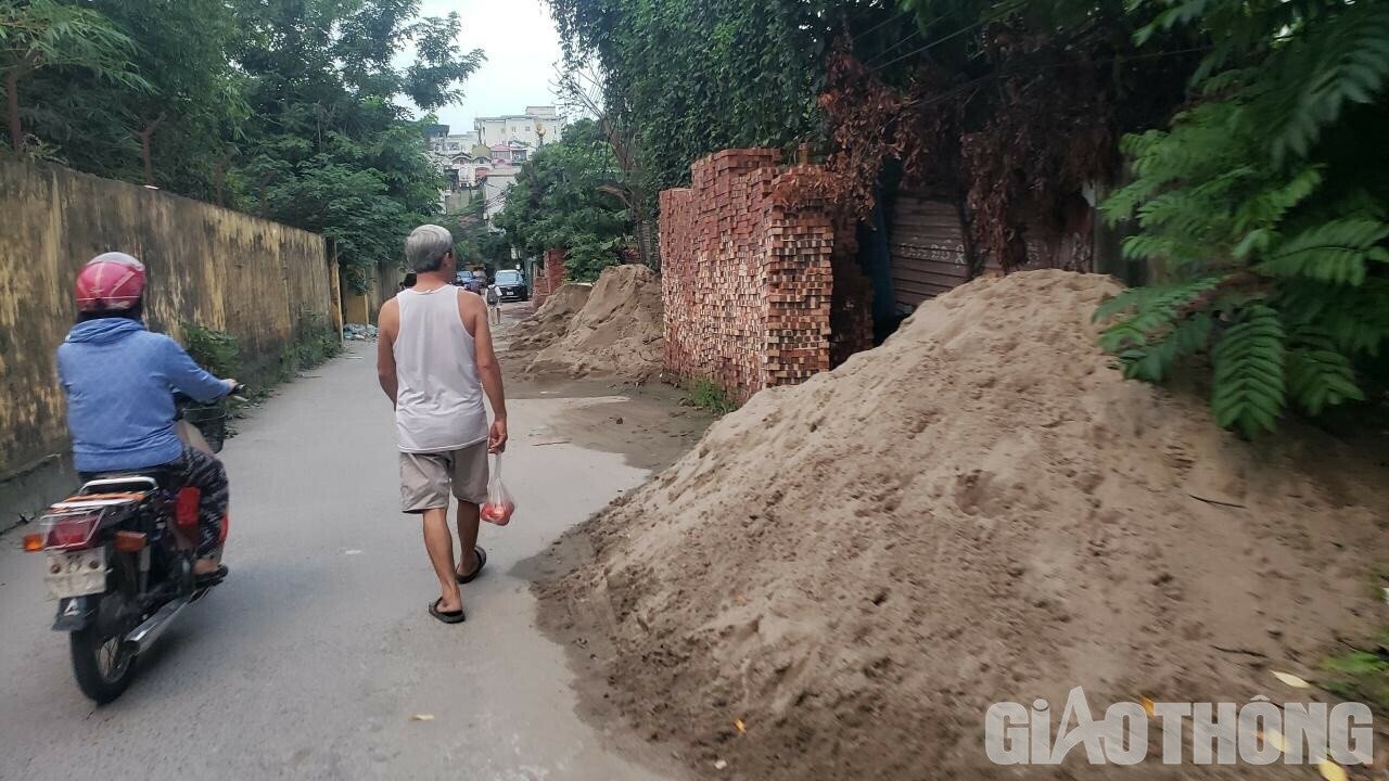 "Những đống c&aacute;t kh&ocirc;ng được che chắn n&ecirc;n ng&agrave;y nắng th&igrave; bụi m&ugrave;, ng&agrave;y mưa th&igrave; c&aacute;t tr&agrave;n ra khắp đường, bẩn thỉu. C&ograve;n đối với những vi&ecirc;n gạch được xếp cao cũng c&oacute; thể rơi bất cứ l&uacute;c n&agrave;o. Ch&uacute;ng t&ocirc;i sợ nhất trẻ con đi học về qua những b&atilde;i tập kết vật liệu x&acirc;y dựng n&agrave;y sẽ gặp nguy hiểm", anh An, ở phường Hạ Đ&igrave;nh chia sẻ.