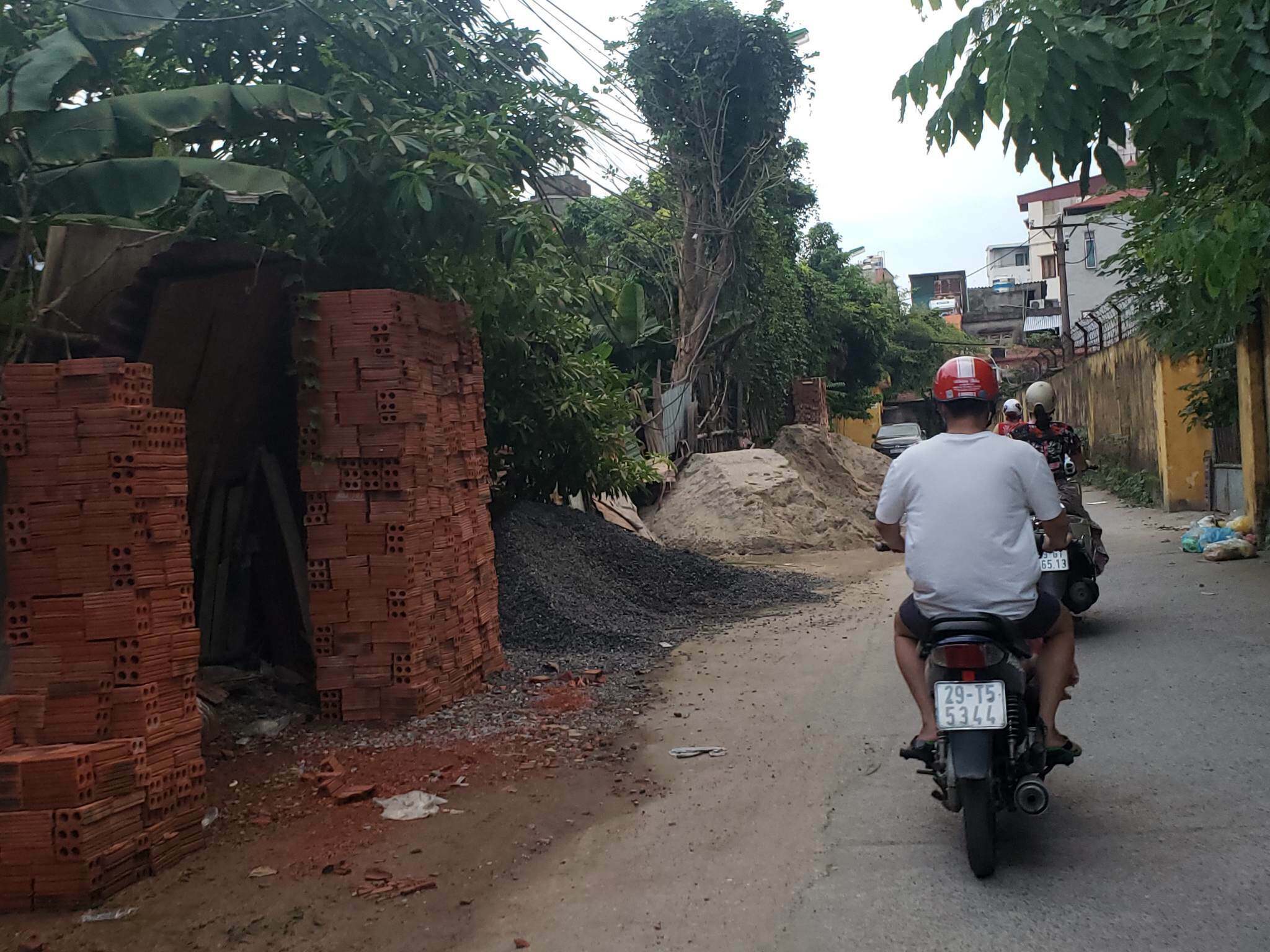 Tại ng&otilde; 129 đường Nguyễn Xiển, cả một con đường rộng khoảng 7m bị những đống gạch, c&aacute;t, đ&aacute;&hellip; đổ ngổn ngang, chiếm hết nửa đường. Trong khi đ&oacute;, khu vực n&agrave;y c&oacute; lưu lượng phương tiện đi qua đ&ocirc;ng, gồm cả học sinh v&agrave; người cao tuổi...