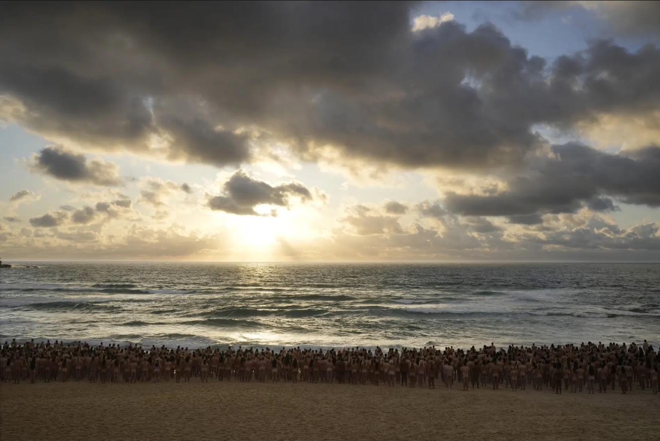 Tất cả 2.500 người mẫu v&agrave; ekip chụp ảnh đ&atilde; đến b&atilde;i biển Bondi từ s&aacute;ng sớm để c&oacute; thể ho&agrave;n th&agrave;nh dự &aacute;n chụp ảnh nghệ thuật, n&acirc;ng cao nhận thức về c&aacute;c bệnh ung thư da do nhiếp ảnh gia Spencer Tunick thực hiện.