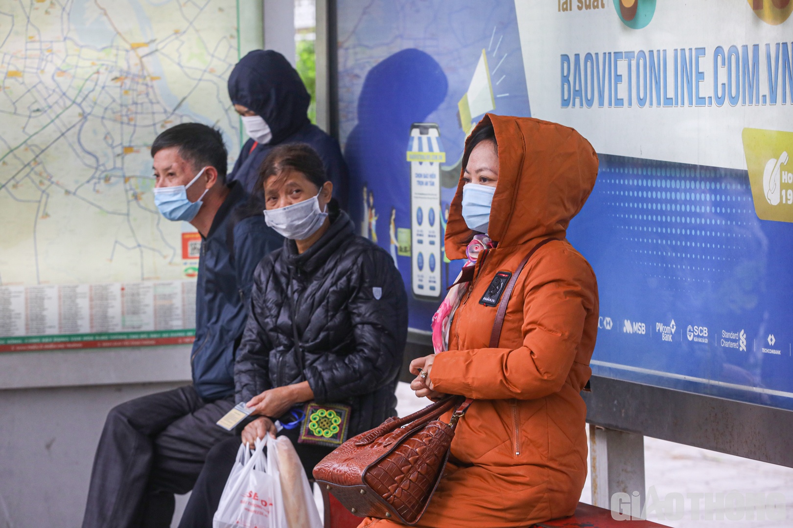 Để tr&aacute;nh r&eacute;t, nhiều người lựa chọn c&aacute;c phương tiện c&ocirc;ng cộng để di chuyển (trong ảnh: H&agrave;nh kh&aacute;ch ngồi chờ xe bu&yacute;t tr&ecirc;n phố Đ&agrave;o Tấn).