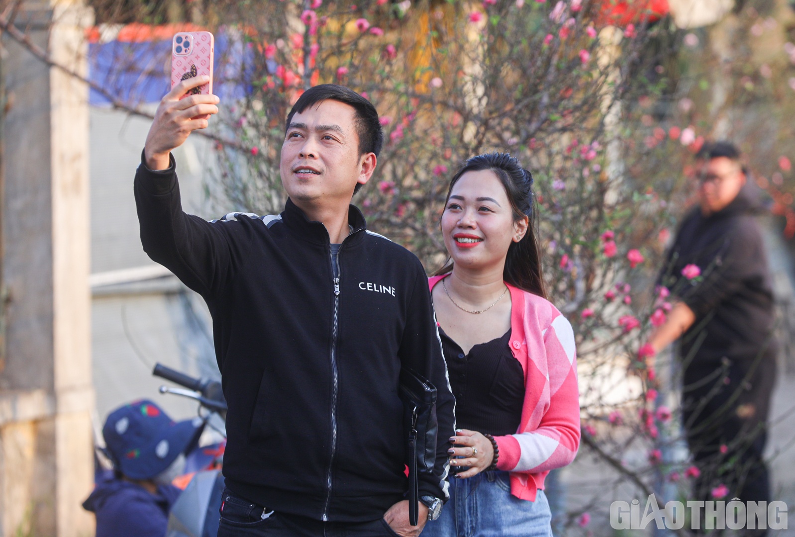 Nhiều người vừa dạo bước ngắm hoa vừa tranh thủ lưu lại khoảnh khắc đẹp b&ecirc;n c&agrave;nh đ&agrave;o đầu m&ugrave;a.