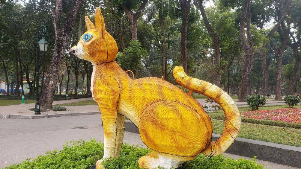 Theo ghi nhận của PV, m&ocirc; h&igrave;nh linh vật m&egrave;o được đặt ngay ở cổng v&agrave;o C&ocirc;ng vi&ecirc;n Thống Nhất ở đường Trần Nh&acirc;n T&ocirc;ng cao khoảng 2m v&agrave; d&agrave;i khoảng 3m, được quấn bằng d&acirc;y thừng b&ecirc;n ngo&agrave;i để tạo h&igrave;nh, c&oacute; kết hợp đ&egrave;n chiếu s&aacute;ng.