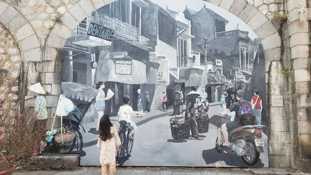 Khu phố b&iacute;ch họa Ph&ugrave;ng Hưng những ng&agrave;y cuối năm đang thu h&uacute;t rất nhiều người đến chụp ảnh, checkin. Một b&eacute; g&aacute;i dừng lại ngắm rất l&acirc;u v&agrave;o bức tranh phố phường H&agrave; Nội.