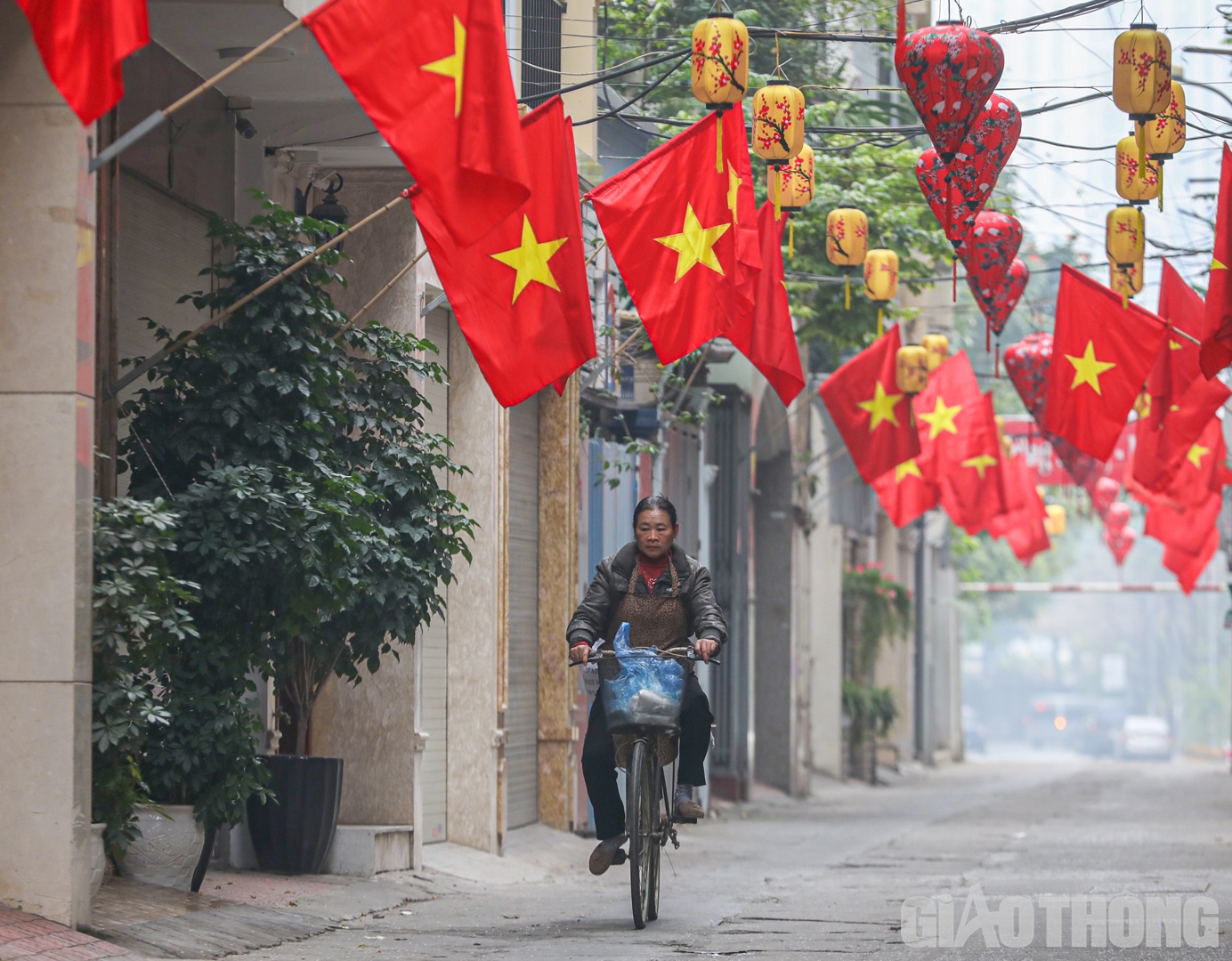 Người phụ nữ đạp xe b&aacute;n muối đầu năm trong con ng&otilde; nhỏ nổi bật với cờ đỏ sao v&agrave;ng.