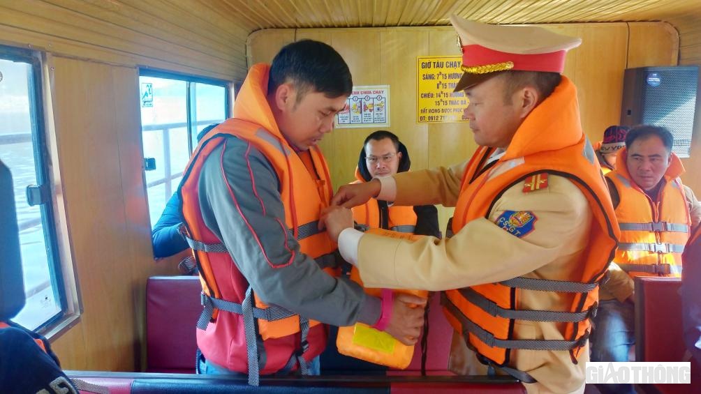 C&aacute;n bộ chiến sĩ Đội CSGT đường thủy hướng dẫn người d&acirc;n thao t&aacute;c mặc &aacute;o phao đ&uacute;ng c&aacute;ch.