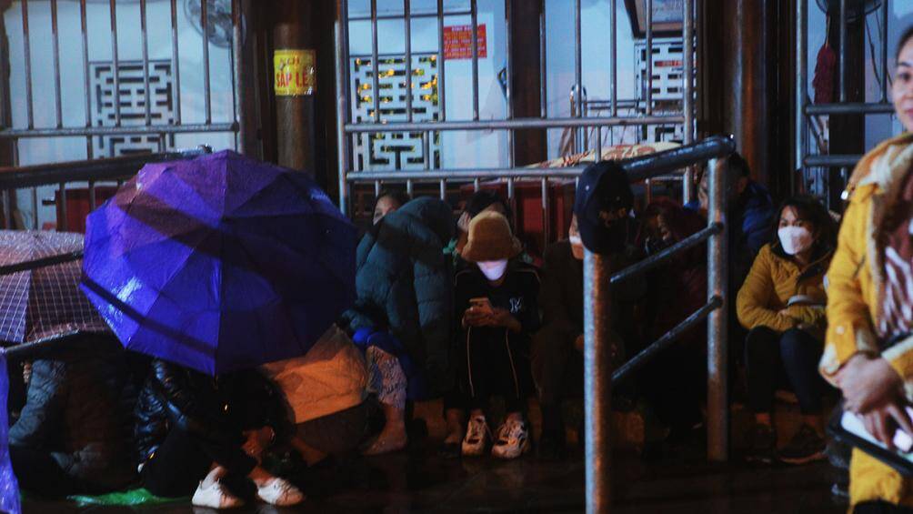 Mong muốn l&agrave; những người đầu ti&ecirc;n được nhận l&aacute; ấn, nhiều người d&acirc;n đ&atilde; thức th&acirc;u đ&ecirc;m dưới mưa r&eacute;t. C&oacute; người che &ocirc;, người căng mảnh &aacute;o mưa ngồi ngủ gật chờ trời s&aacute;ng.