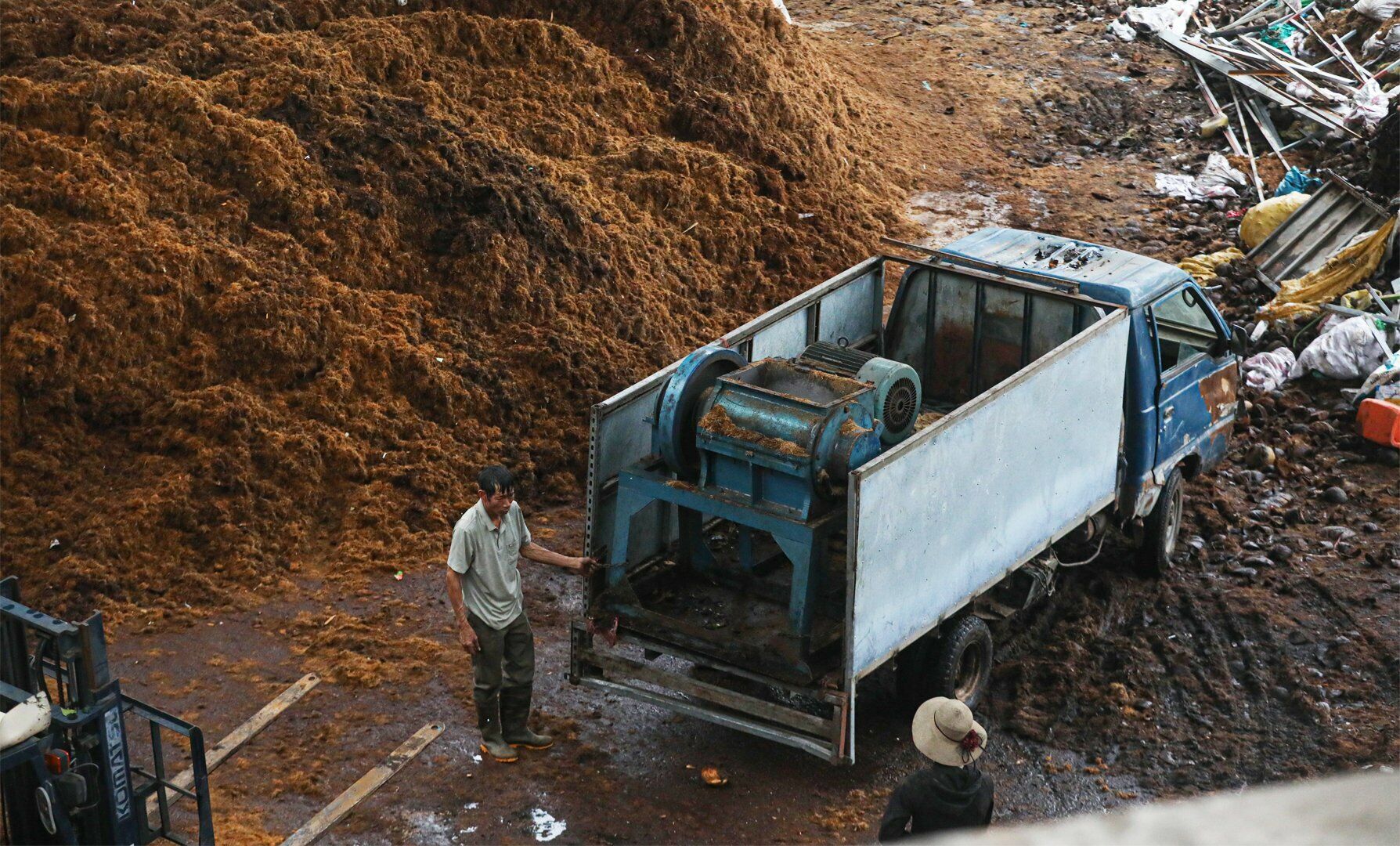 Dưới ch&acirc;n cầu, rất nhiều xưởng sản xuất xơ dừa với những đống xơ chất cao gần đến mặt dưới của cầu Thăng Long.