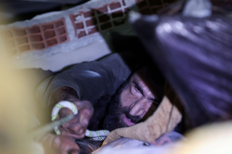 Đ&ocirc;i ch&acirc;n của &ocirc;ng Abdulalim bị kẹt dưới đống b&ecirc; t&ocirc;ng nhưng &ocirc;ng vẫn tỉnh t&aacute;o v&agrave; c&oacute; thể tr&ograve; chuyện với c&aacute;c nh&acirc;n vi&ecirc;n cứu hộ. 
Trong ảnh, &ocirc;ng Abdulalim nắm lấy sợi d&acirc;y thừng khi đội cứu hộ t&igrave;m c&aacute;ch k&eacute;o &ocirc;ng ra khỏi đống đổ n&aacute;t. Ảnh - Reuters