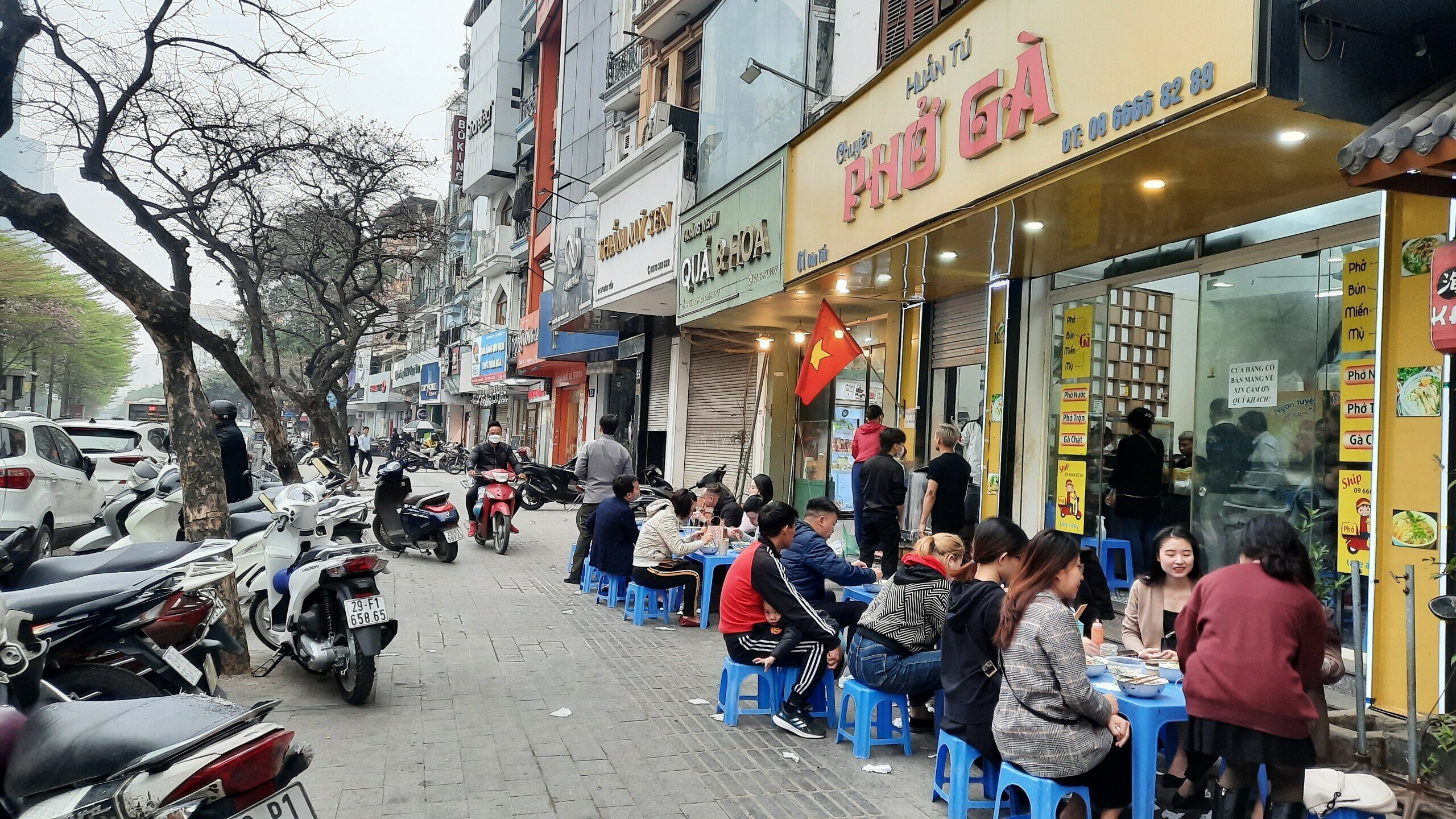 Qu&aacute;n phở g&agrave; (địa chỉ 61 Đ&agrave;o Tấn, phường Ngọc Kh&aacute;nh) ngang nhi&ecirc;n xếp h&agrave;ng d&agrave;i b&agrave;n, ghế ra vỉa h&egrave; để phục vụ kh&aacute;ch h&agrave;ng ăn uống.