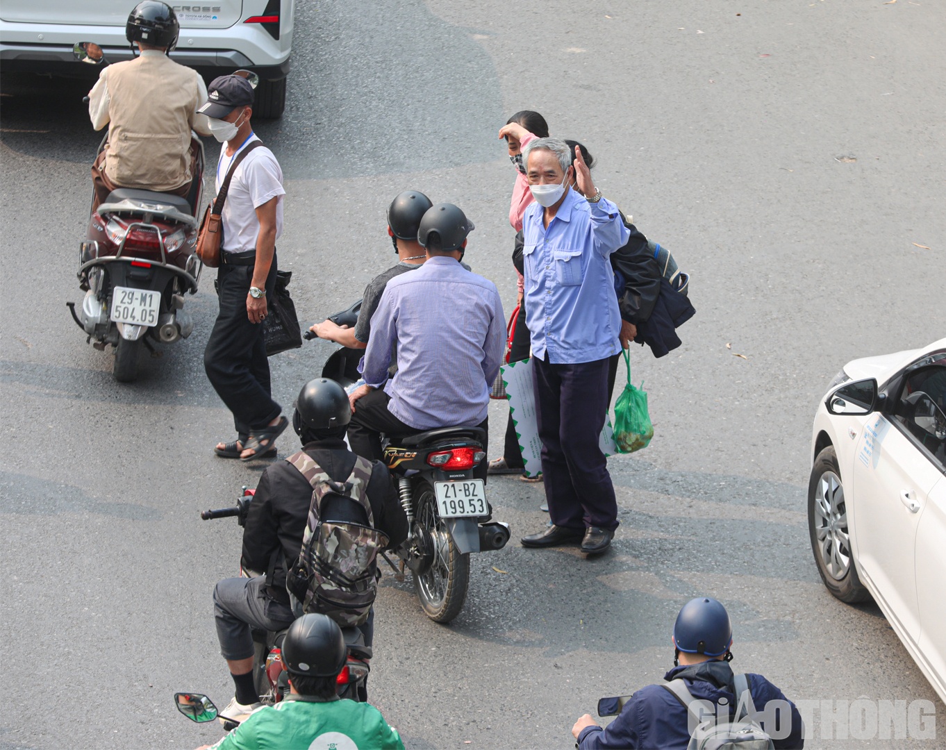 Từng nh&oacute;m người d&agrave;n h&agrave;ng ngang, dắt d&iacute;u nhau l&aacute;ch qua đầu &ocirc; t&ocirc;, xe m&aacute;y đang di chuyển.