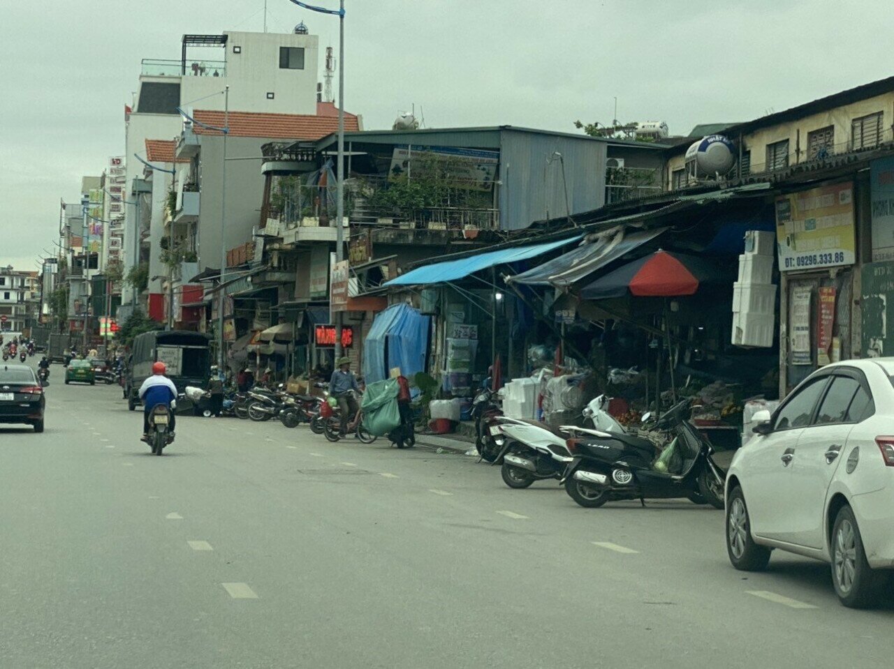 Khu vực qua cổng chợ Giếng Đ&aacute;y, h&agrave;ng h&oacute;a, biển quảng c&aacute;o&hellip; được người d&acirc;n tận dụng để hết ra vỉa h&egrave;.