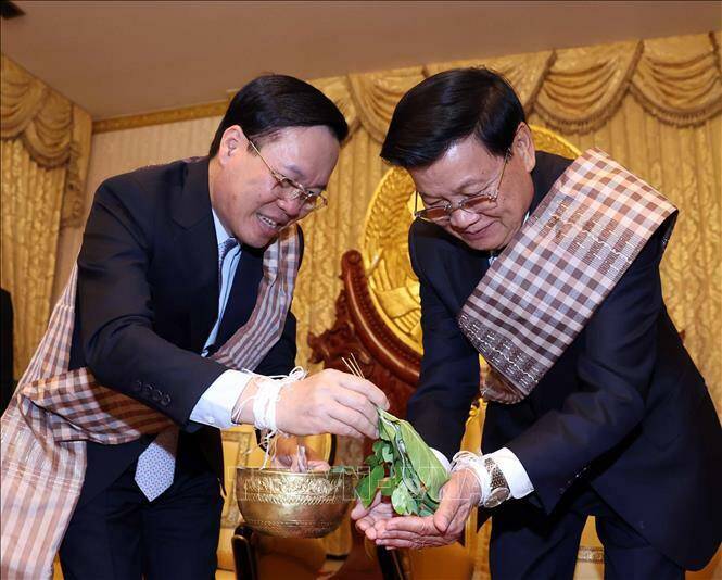 Chủ tịch nước V&otilde; Văn Thưởng v&agrave; Tổng B&iacute; thư, Chủ tịch nước L&agrave;o Thongloun Sisoulith tại lễ buộc chỉ cổ tay cầu may nh&acirc;n dịp Tết cổ truyền Bunpimay của L&agrave;o.