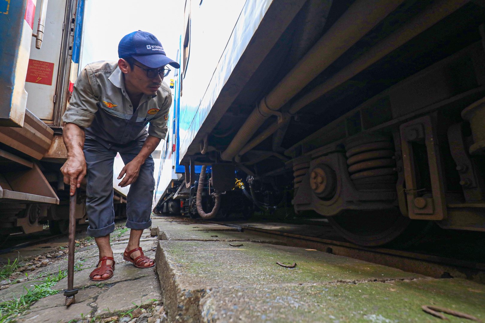 C&ocirc;ng nh&acirc;n kh&aacute;m chữa toa xe kiểm tra bộ phận chạy trước khi t&agrave;u xuất ph&aacute;t