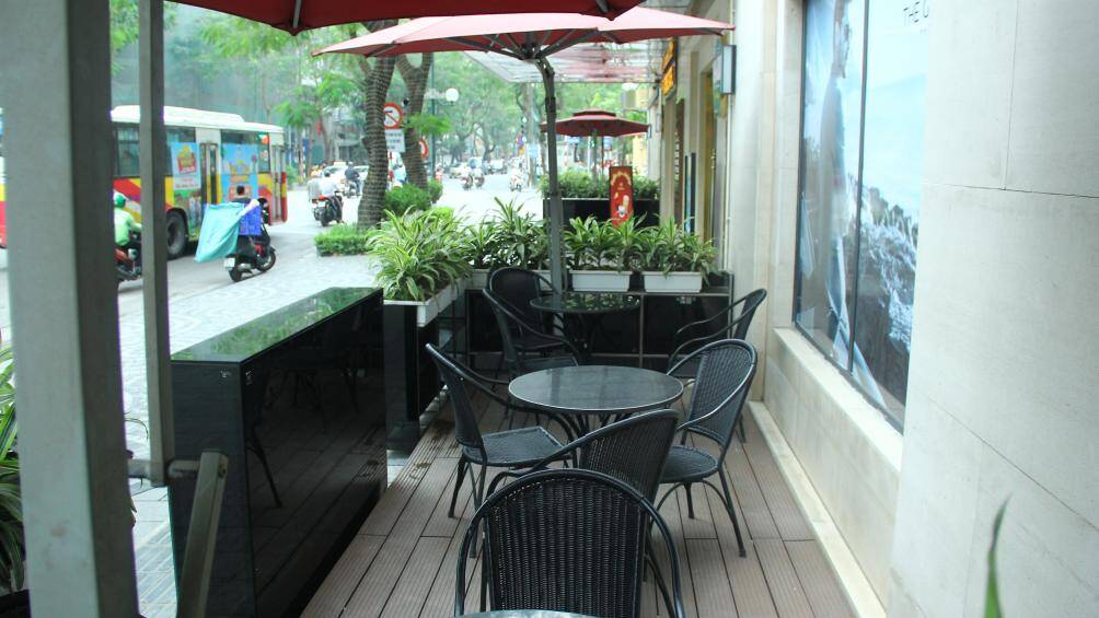 Mặt s&agrave;n được xếp bằng những tấm gỗ, b&agrave;n ghế được để đơn giản nhưng view kh&aacute; thu h&uacute;t do nằm ở giữa ng&atilde; tư.