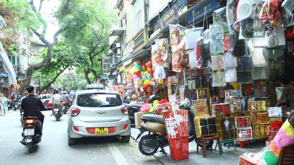 Tương tự, c&aacute;c hộ kinh doanh tại phố H&agrave;ng M&atilde; (quận Ho&agrave;n Kiếm) ngang nhi&ecirc;n b&agrave;y b&aacute;n h&agrave;ng h&oacute;a k&iacute;n vỉa h&egrave;, tr&agrave;n xuống cả l&ograve;ng đường.