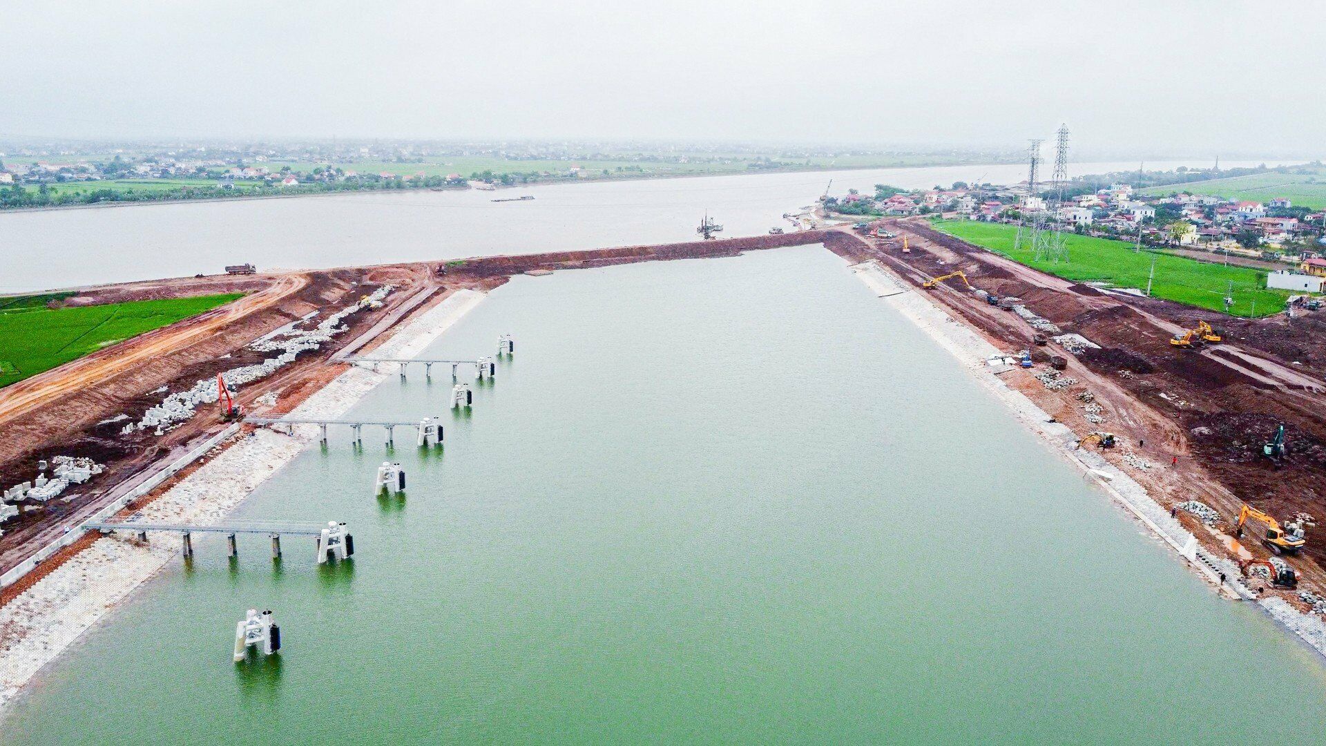 Cụm c&ocirc;ng tr&igrave;nh k&ecirc;nh nối Đ&aacute;y - Ninh Cơ chia l&agrave;m 4 g&oacute;i thầu x&acirc;y lắp ch&iacute;nh gồm: G&oacute;i thầu CV-A2.9-NDTDP: Cầu qua k&ecirc;nh nối Đ&aacute;y - Ninh Cơ; 3 g&oacute;i thầu CV-A2.6-NDTDP, CV-A2.7-NDTDP v&agrave; CV-A2.8-NDTDP x&acirc;y dựng &acirc;u v&agrave; k&ecirc;nh dẫn, được khởi c&ocirc;ng th&aacute;ng 3/2021. Theo đ&oacute;, x&acirc;y dựng k&ecirc;nh nối giữa s&ocirc;ng Đ&aacute;y v&agrave; s&ocirc;ng Ninh Cơ với chiều d&agrave;i khoảng 1km; chiều rộng đ&aacute;y k&ecirc;nh từ 90m - 100m (Ảnh: K&ecirc;nh đ&agrave;o)