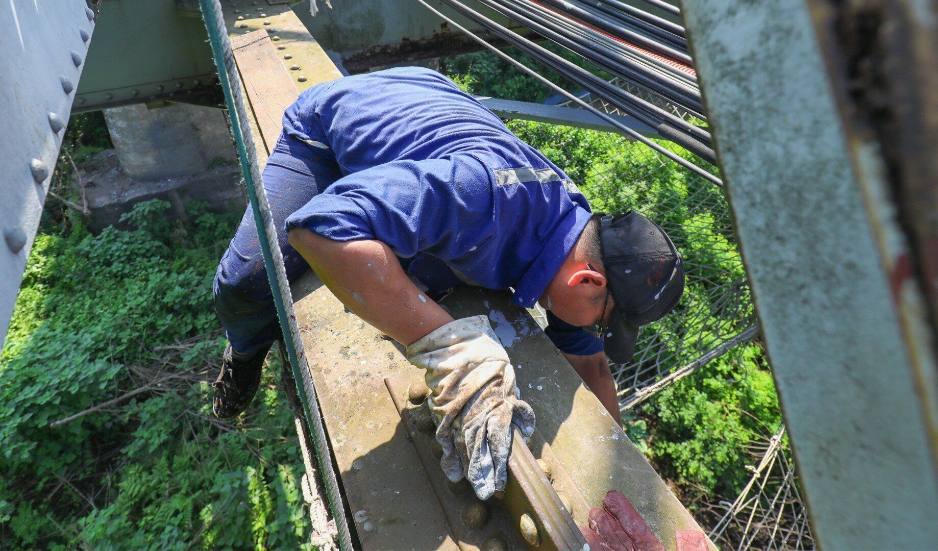 C&ocirc;ng nh&acirc;n b&aacute;m c&aacute;c thanh th&eacute;p, sơn ph&iacute;a dưới, mặt b&ecirc;n