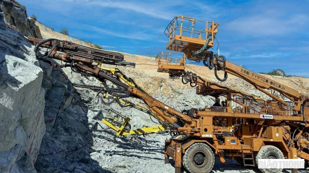 Những mảng đ&aacute; khối ki&ecirc;n cố đ&atilde; được khoan n&aacute;t tạo miệng hầm dưới sự vận h&agrave;nh của những r&ocirc; bốt hiện đại v&agrave; được m&aacute;y x&uacute;c lật hốt dọn đưa l&ecirc;n xe tải chở ra b&atilde;i nghiền.