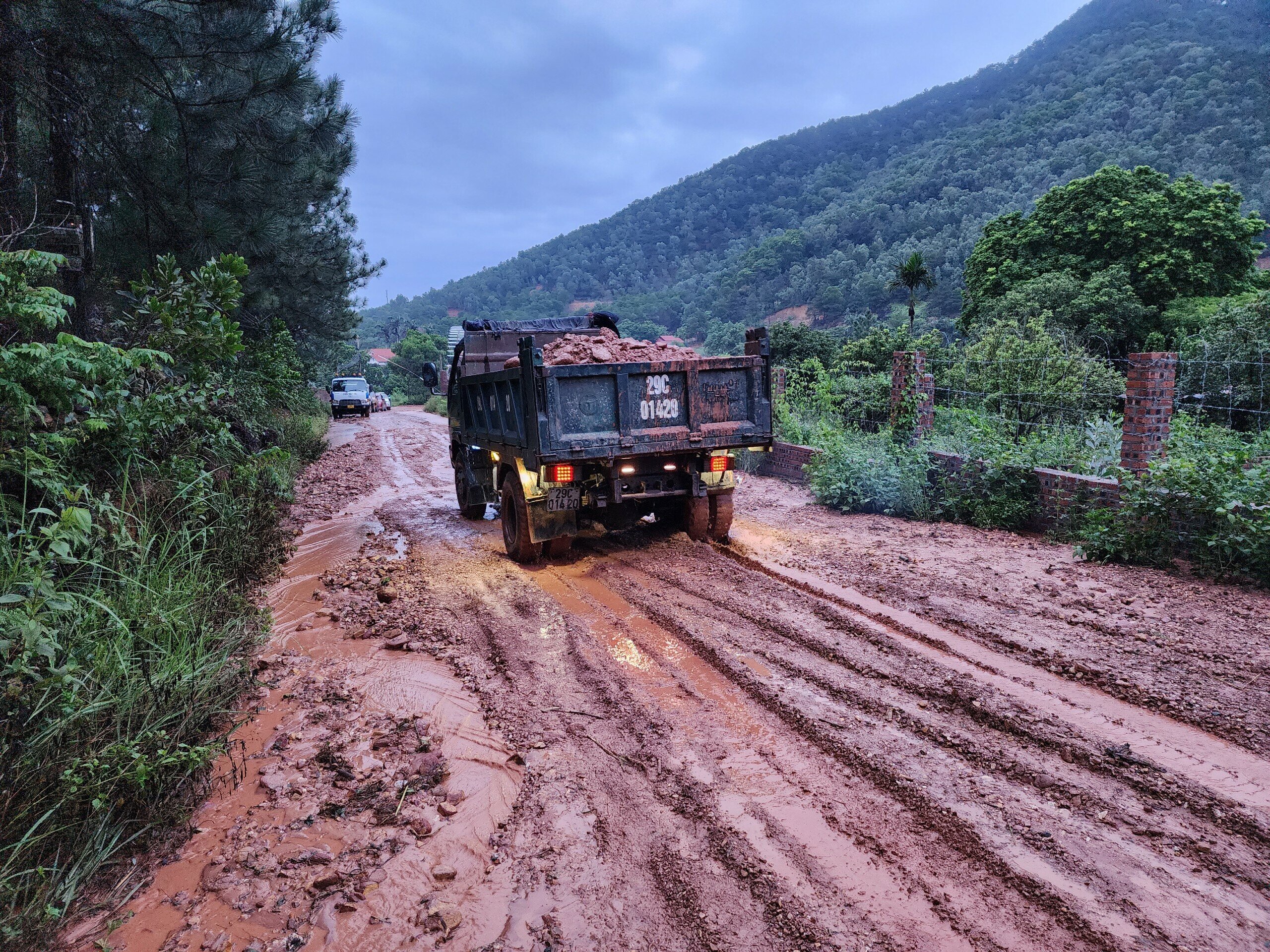 Hai chiếc m&aacute;y x&uacute;c c&ugrave;ng những xe &ocirc; t&ocirc; tải cũng được thu&ecirc; đến để di chuyển đất đ&aacute; ra khỏi khu vực bị b&ugrave;n đất bủa v&acirc;y.