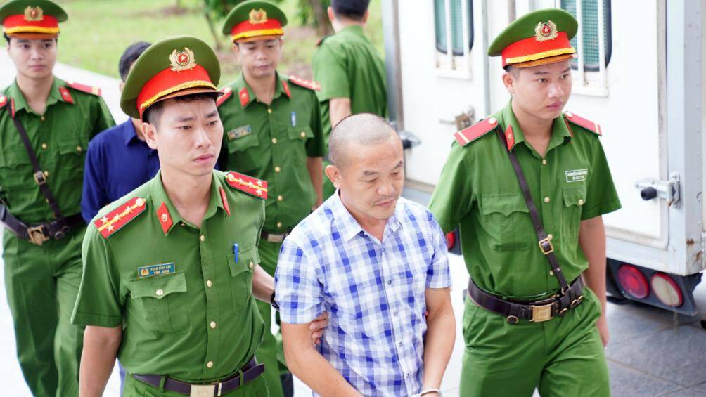 S&aacute;ng 25/8, cảnh s&aacute;t dẫn giải 15 bị c&aacute;o trong vụ n&acirc;ng khống gi&aacute; c&acirc;y xanh khi trồng tại H&agrave; Nội ra x&eacute;t xử.