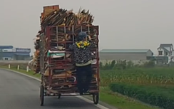 Đội mũ bảo hiểm đu bám xe tự chế chở hàng lấp mặt